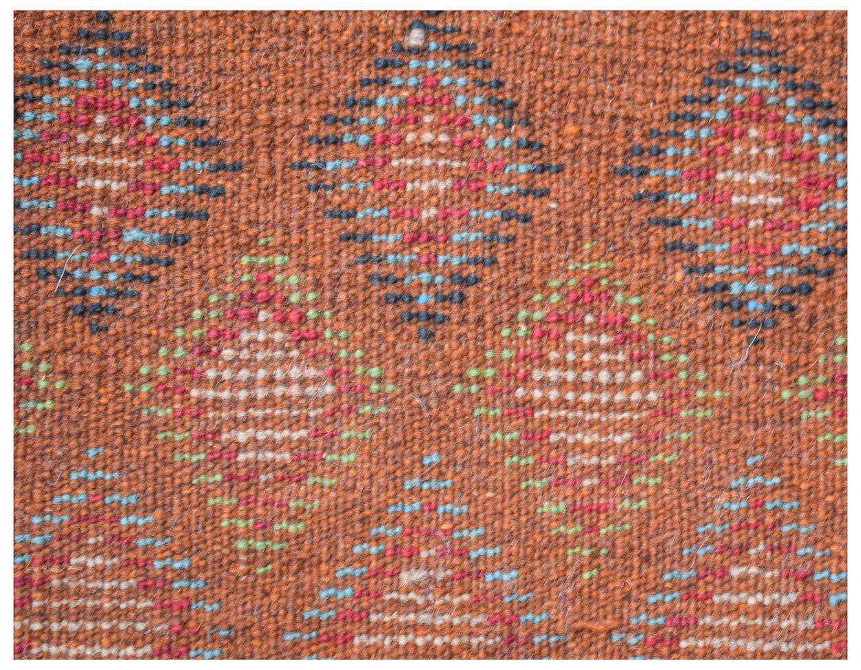 Handmade Afghan Pashm rug featuring a repeating diamond pattern in red, blue, and ivory on brown.