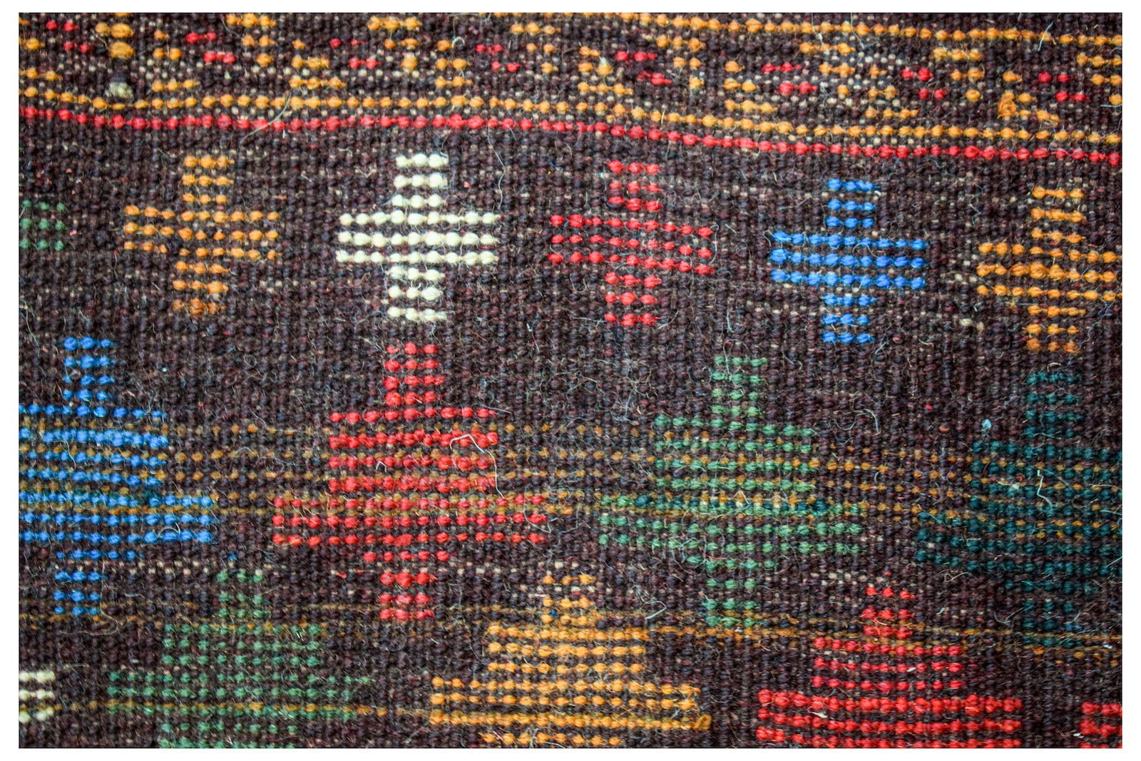 Handmade Afghan Pashm rug featuring a dark brown wool base with colorful geometric cross patterns.