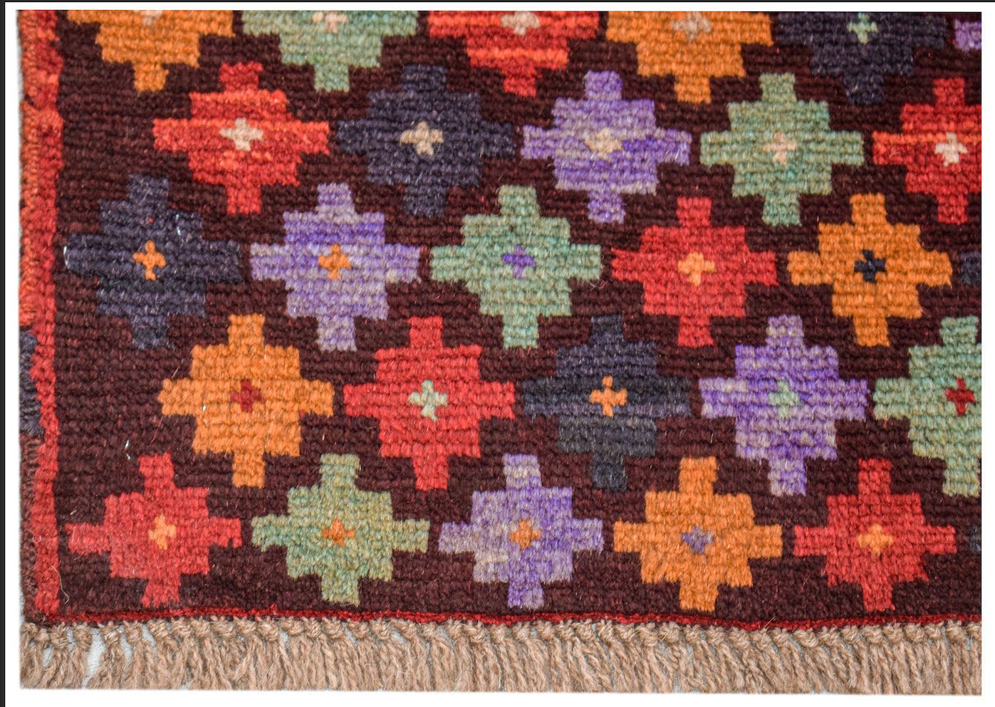 Handmade Afghan Pashm rug featuring a geometric pattern of colorful crosses on a dark brown field.
