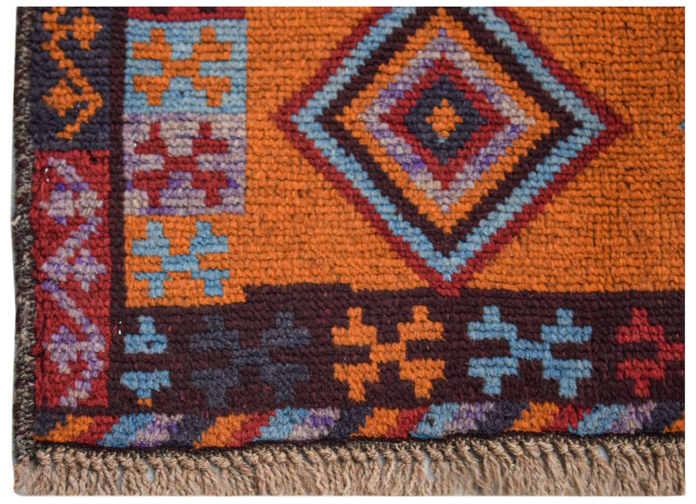 A handmade Afghan Pashm rug featuring a geometric diamond pattern in orange, blue, and dark red.