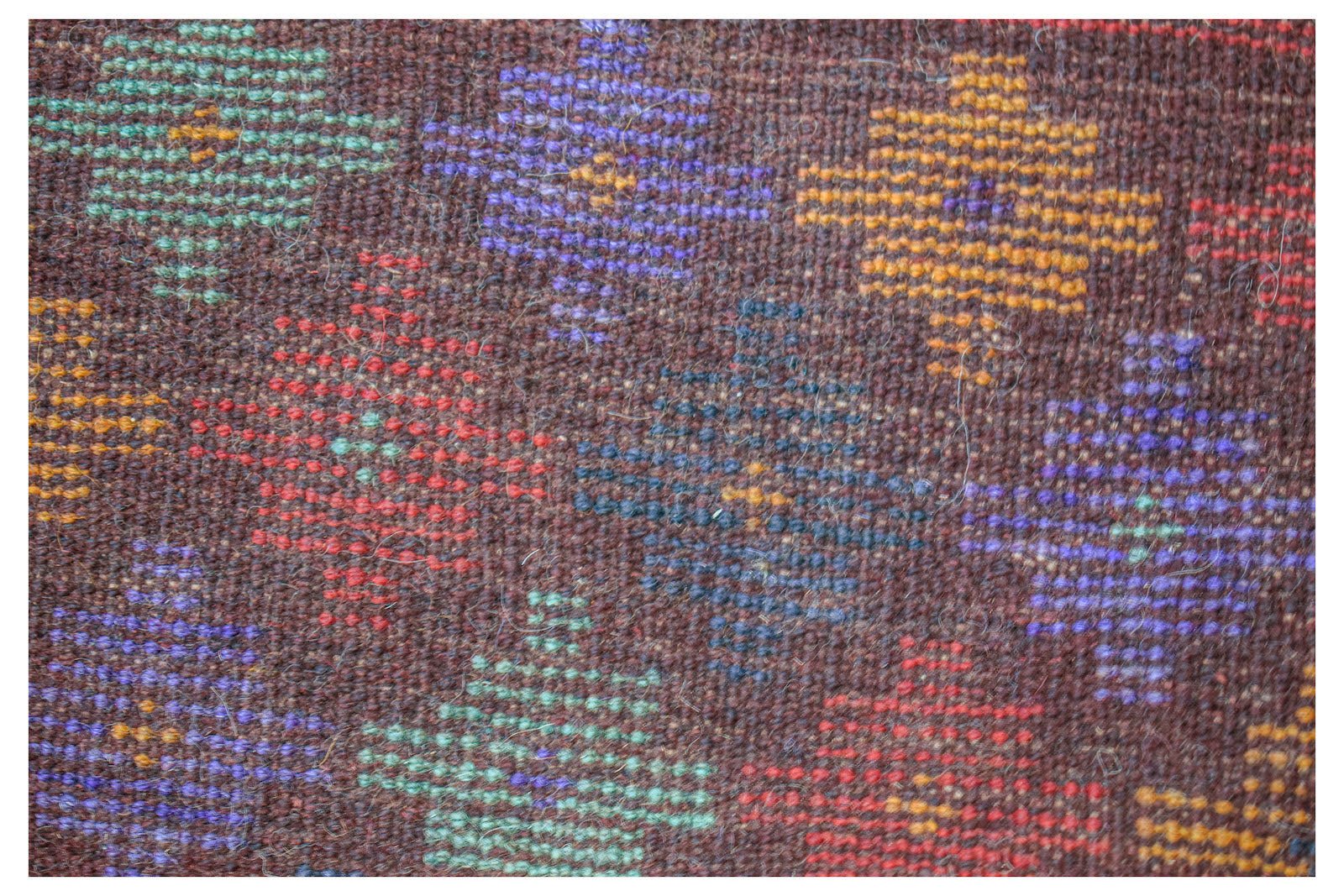 Handmade Afghan Pashm rug featuring a dark brown wool base with colorful geometric diamond motifs.
