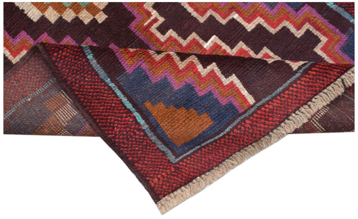 Handmade Afghan Pashm rug featuring a geometric tribal pattern in dark red, blue, and brown tones.