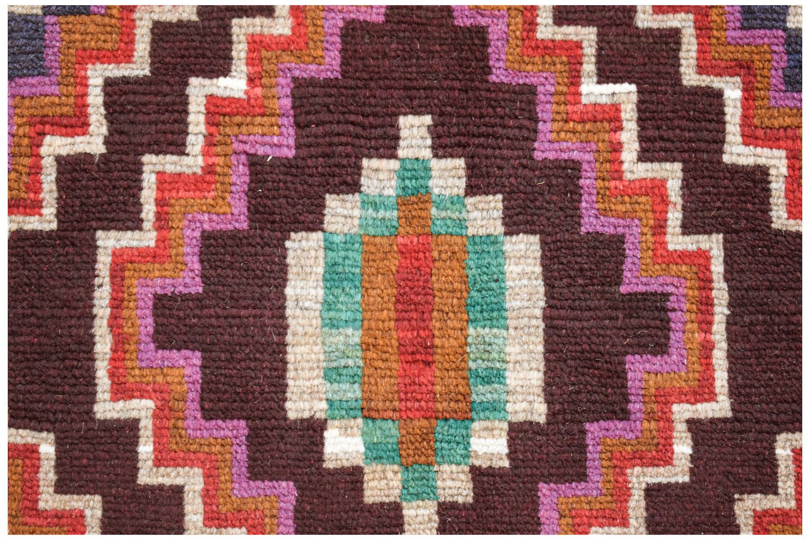 A handmade Afghan Pashm rug featuring a geometric diamond pattern in dark brown, red, and teal.