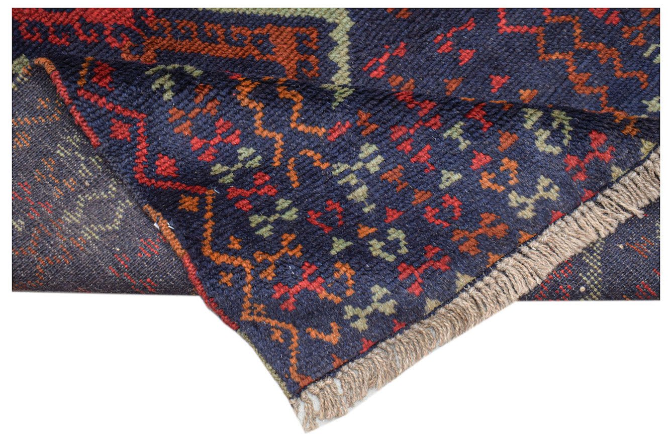 A handmade Afghan Pashm rug featuring a dark blue field with geometric red and green patterns.