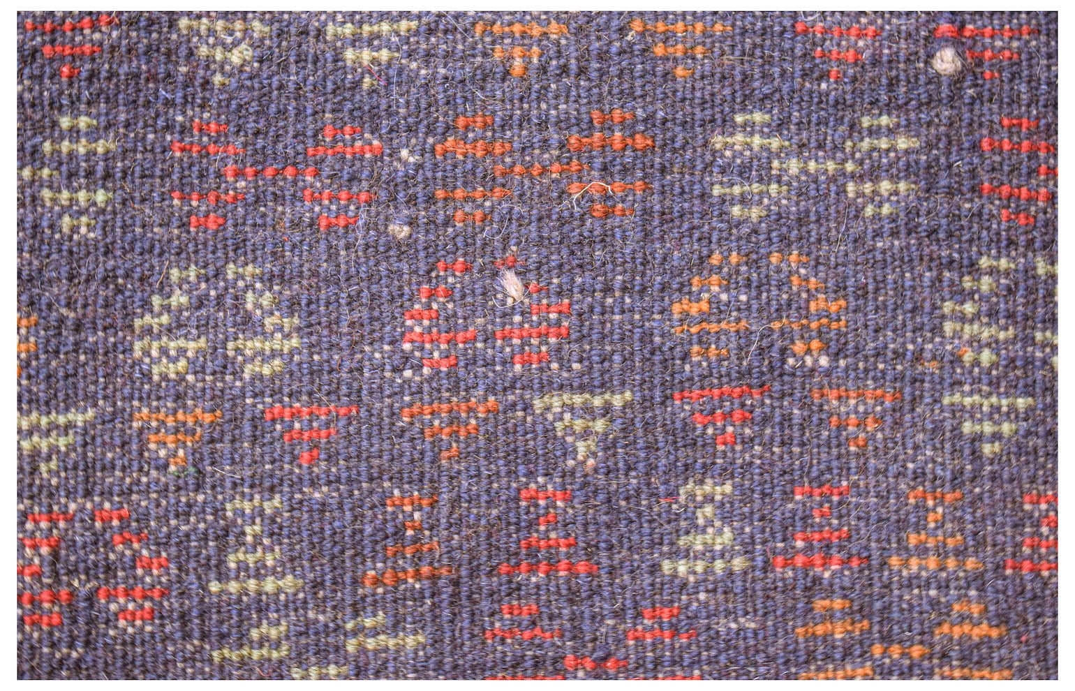 Handmade Afghan Pashm rug featuring a dark blue wool base with small geometric red and tan motifs.