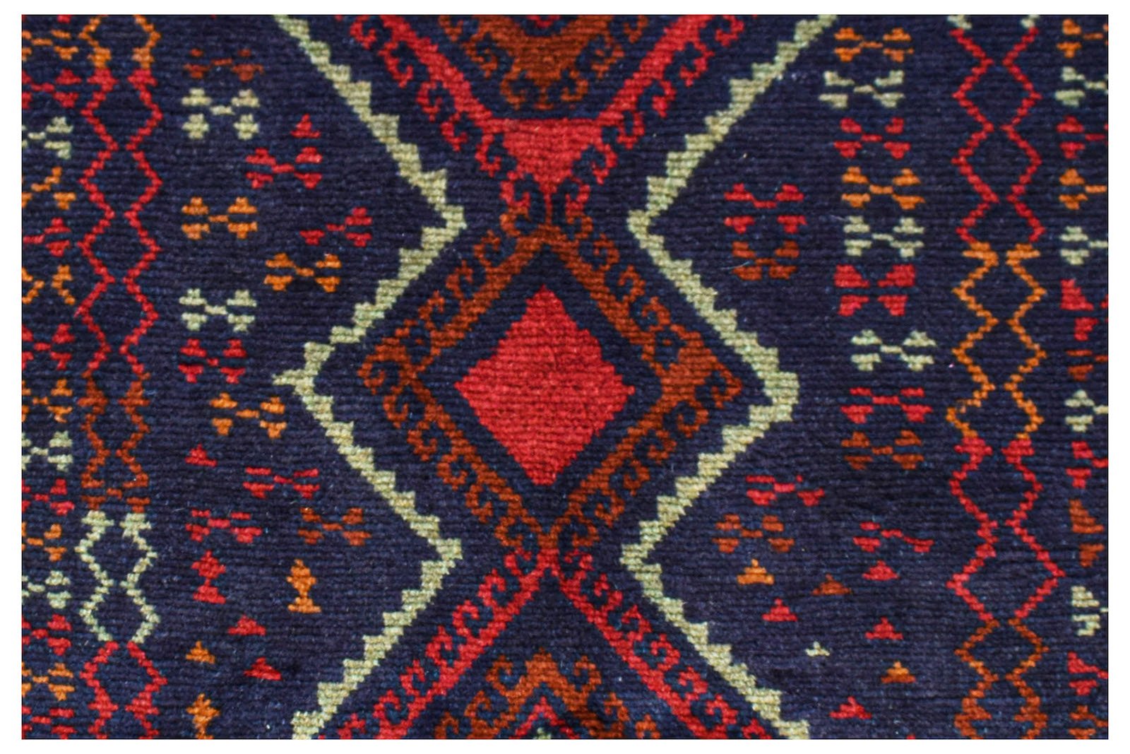A handmade Afghan Pashm rug featuring a geometric diamond pattern in dark red, blue, and ivory.