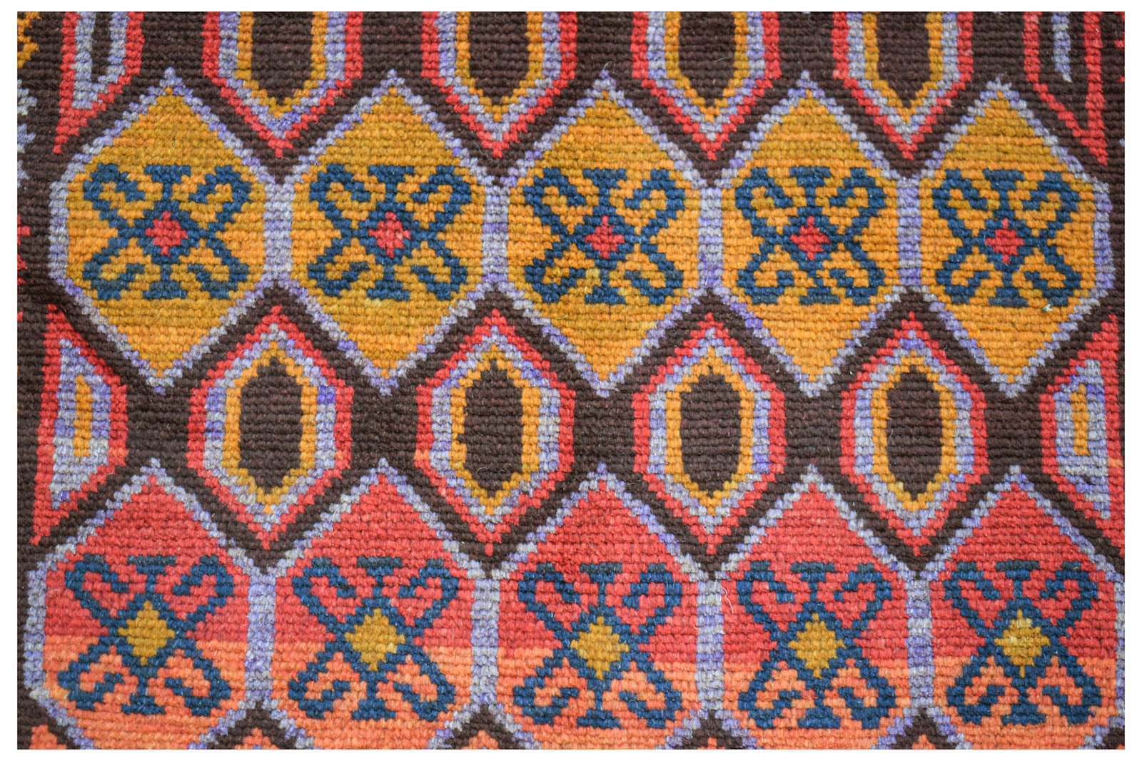 Handmade Afghan Pashm rug featuring a geometric pattern of diamonds in red, orange, and blue.