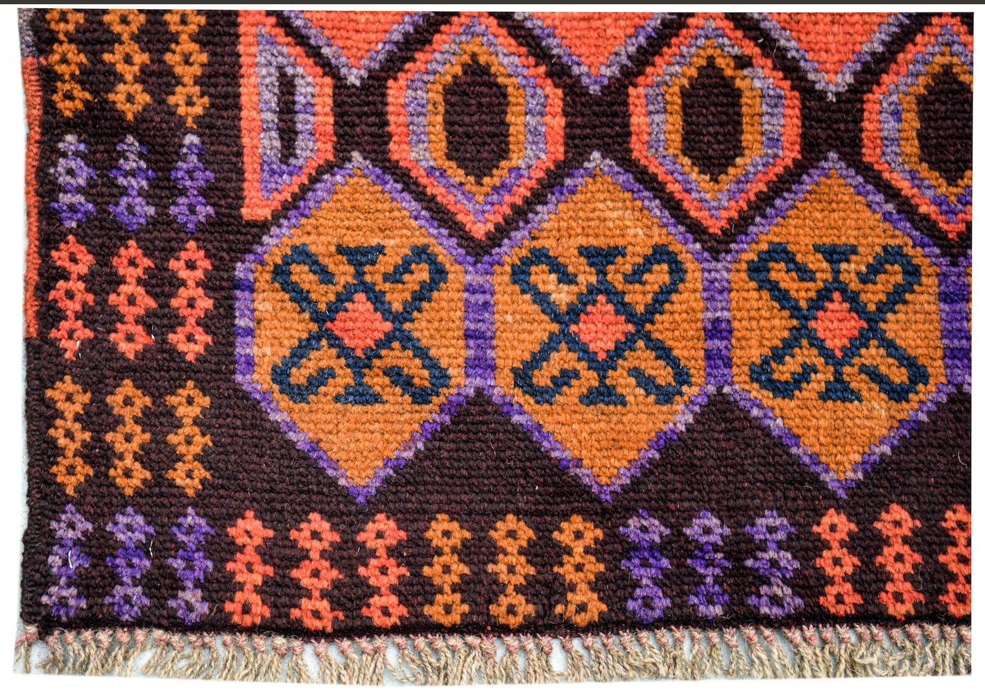 Handmade Afghan Pashm rug featuring geometric diamond patterns in orange, purple, and dark brown.