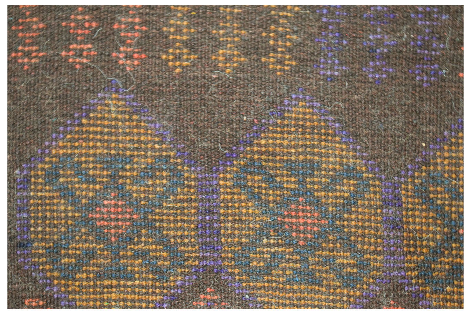 Handmade Afghan Pashm rug featuring a dark brown wool base with geometric patterns in blue and orange.