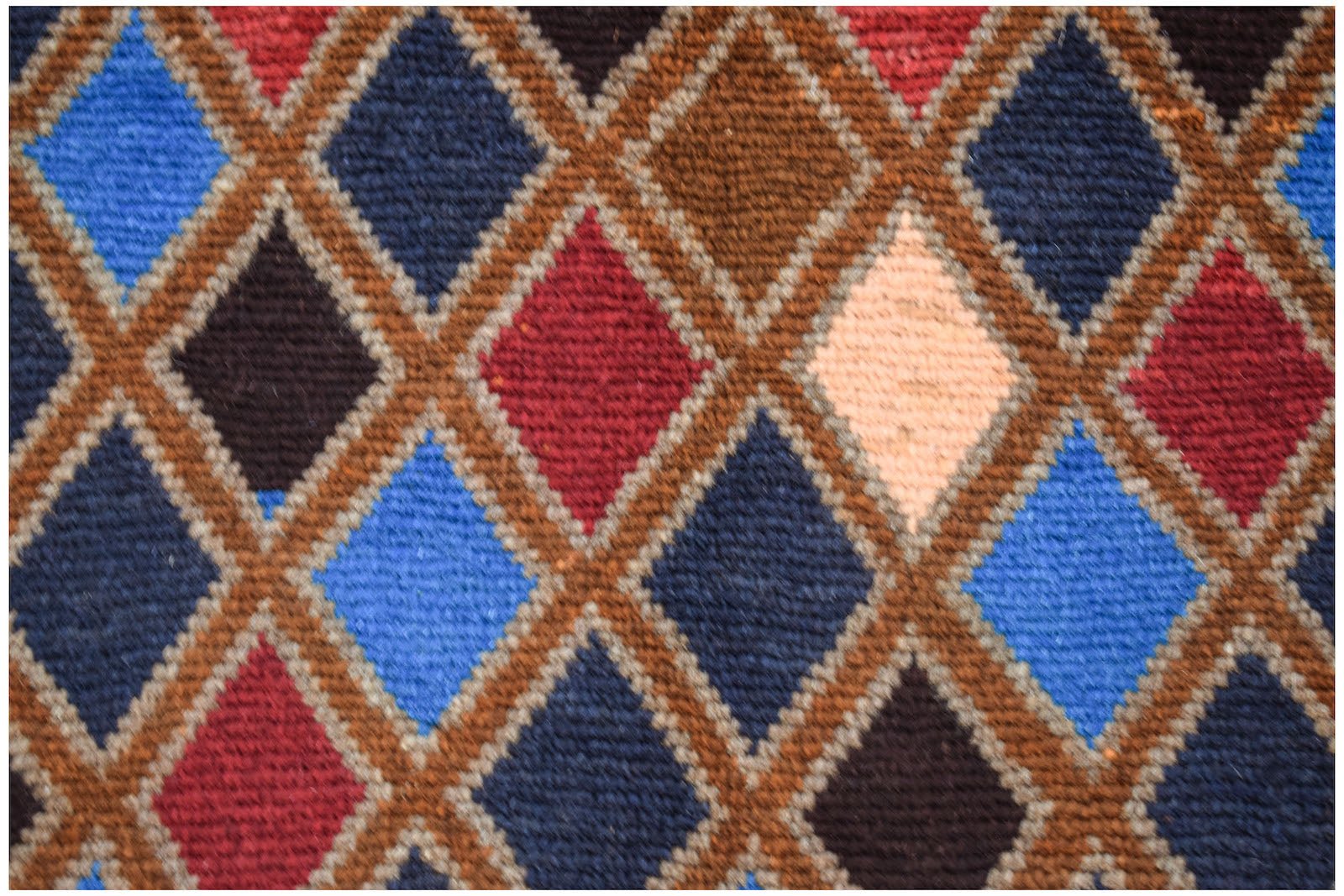 Handmade Afghan Pashm rug featuring a repeating diamond pattern in shades of blue, red, and brown.