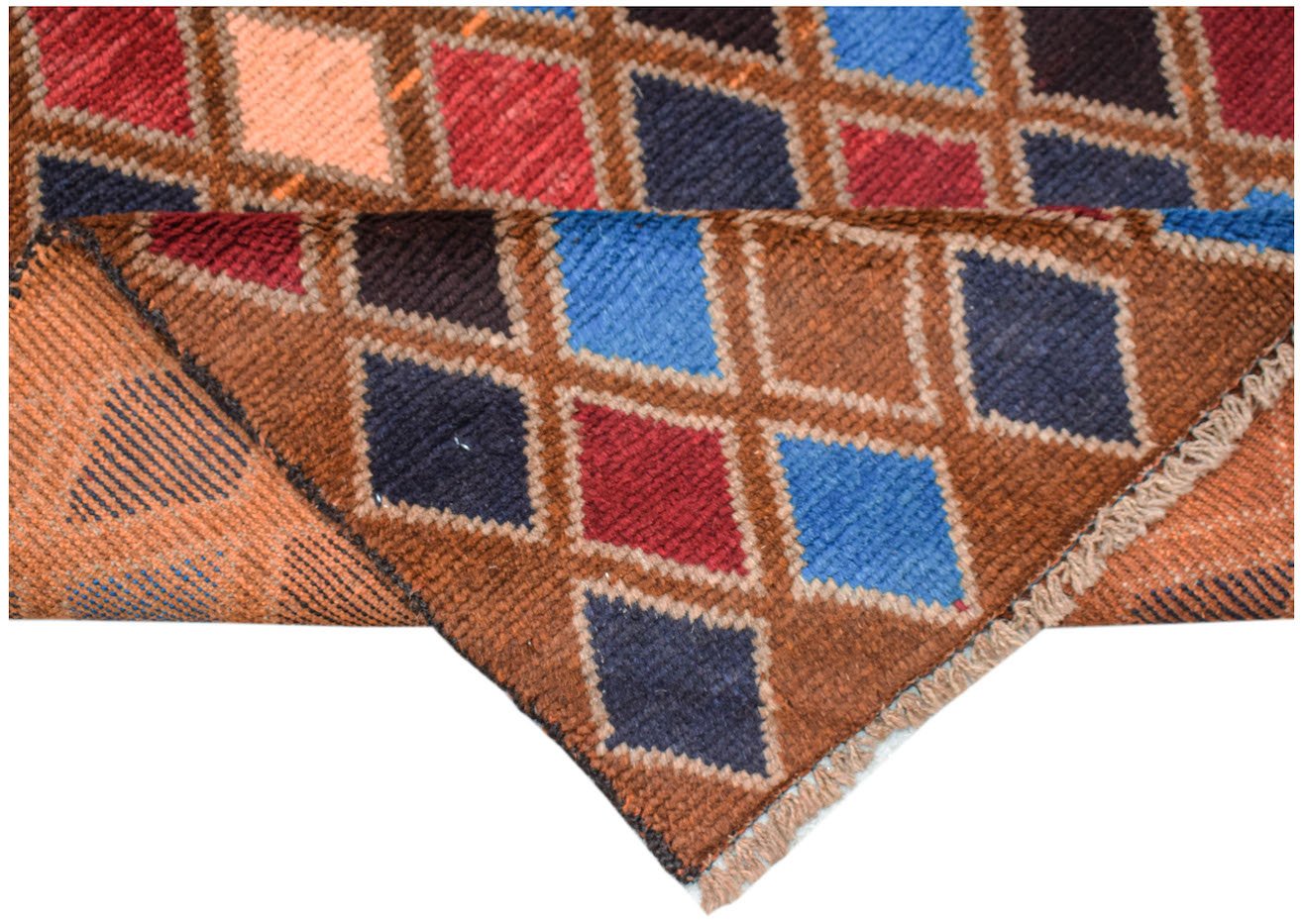 Handmade Afghan Pashm rug featuring a geometric diamond pattern in red, blue, and brown wool.