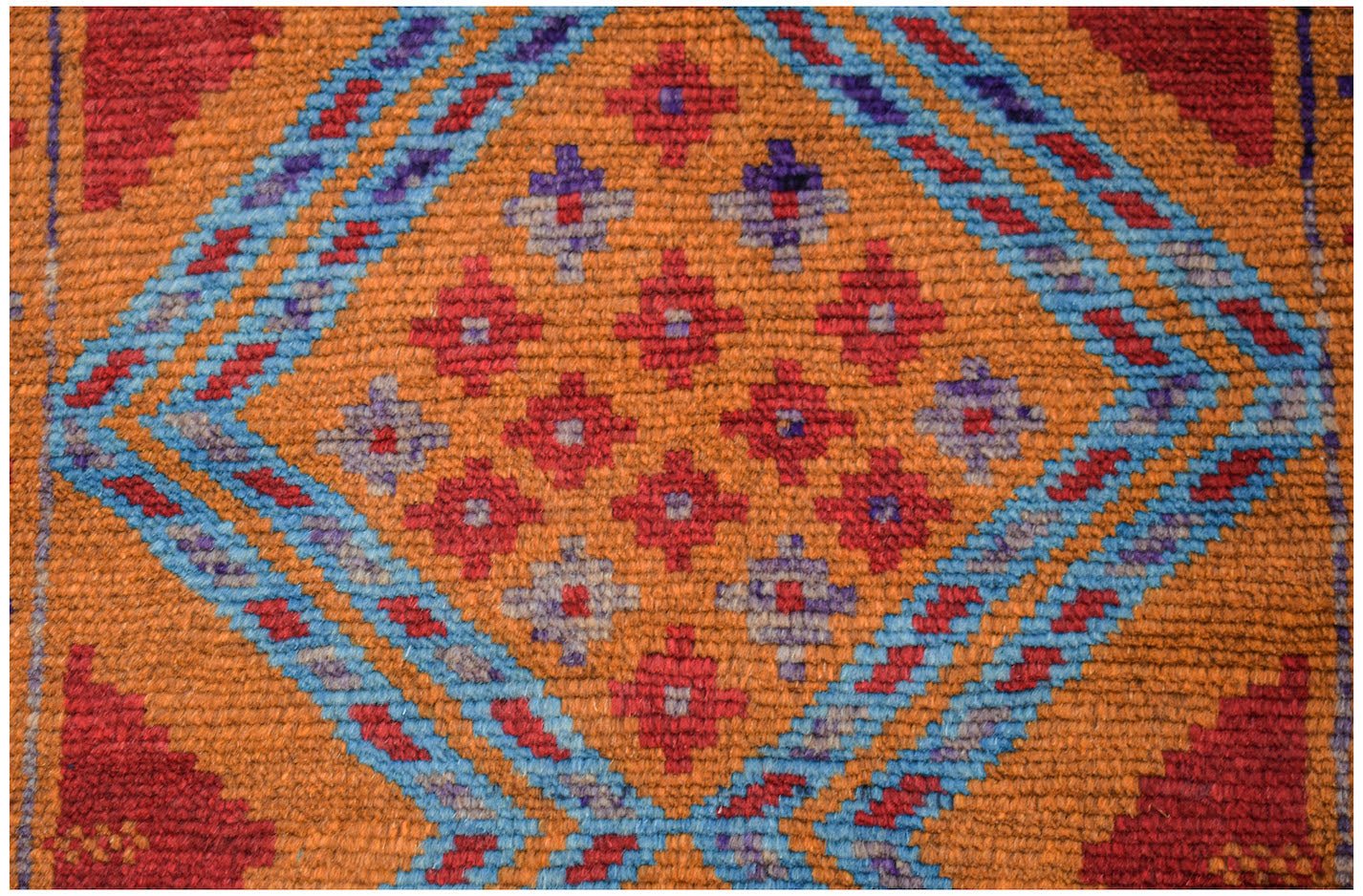 Handmade Afghan wool rug featuring a geometric diamond pattern in red, blue, and orange.
