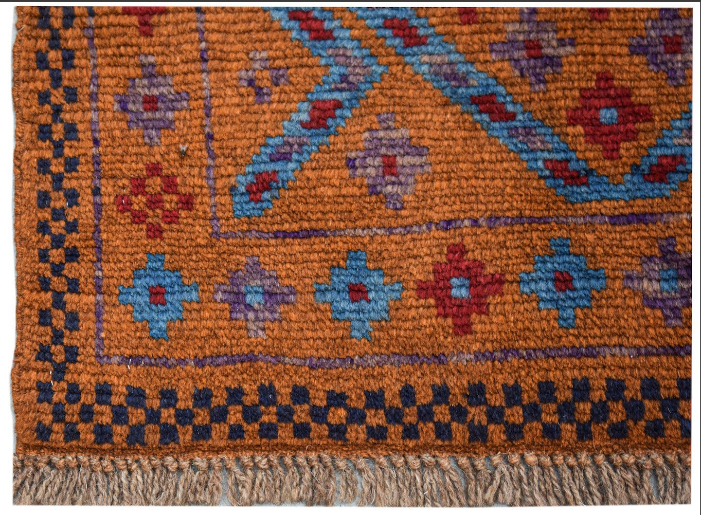 Handmade Afghan wool rug featuring a geometric pattern in blue, red, and purple on an orange field.