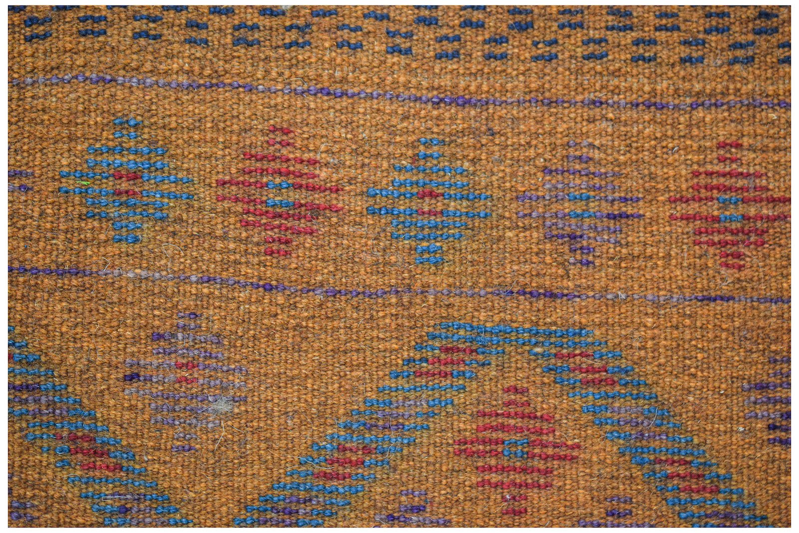 Handmade Afghan Pashm rug featuring a geometric diamond pattern in blue and red on an orange base.