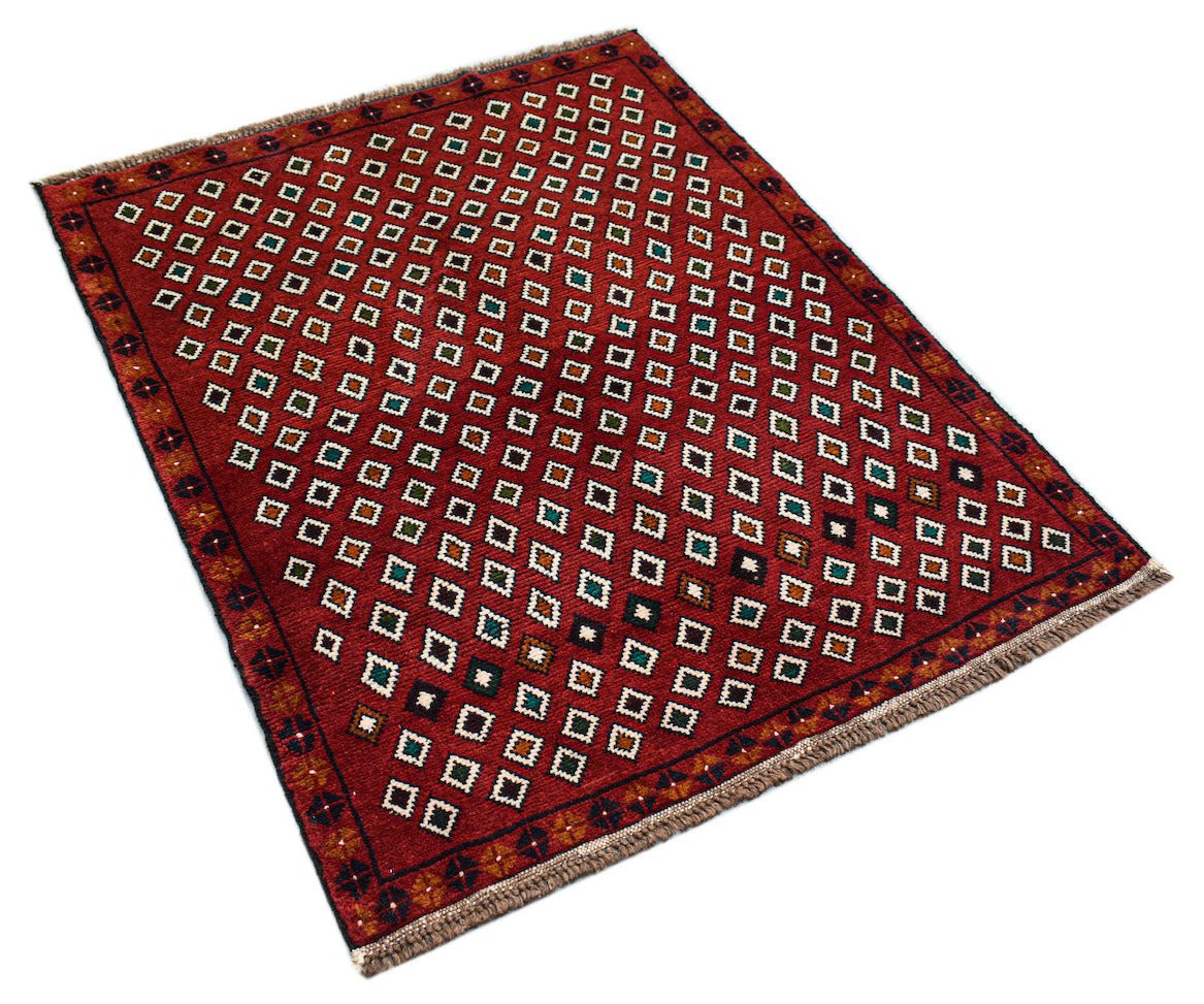 A handmade Afghan Pashm rug featuring a repeating pattern of small white squares on a red field.