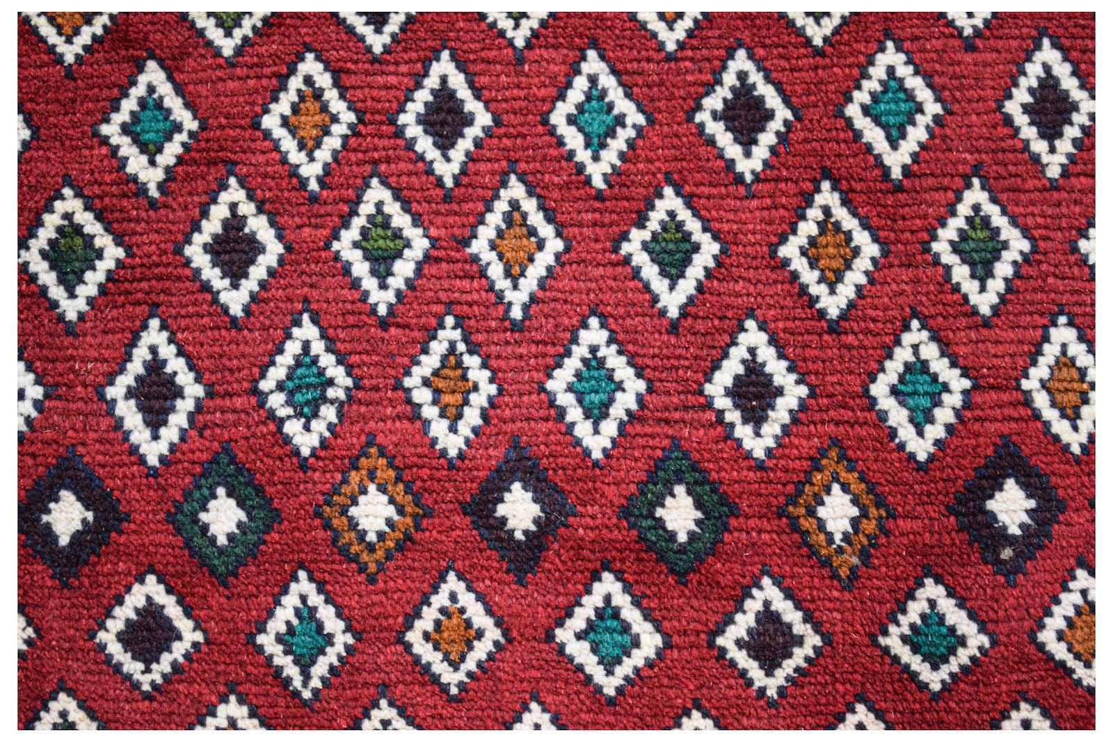 Handmade Afghan Pashm rug featuring a repeating diamond pattern in red, ivory, blue, and brown.