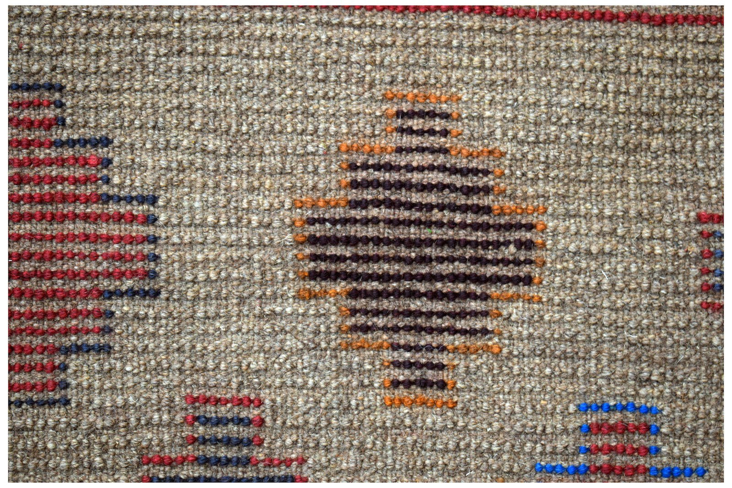 Handmade Afghan Pashm rug featuring geometric diamond patterns in red, blue, and orange on wool.