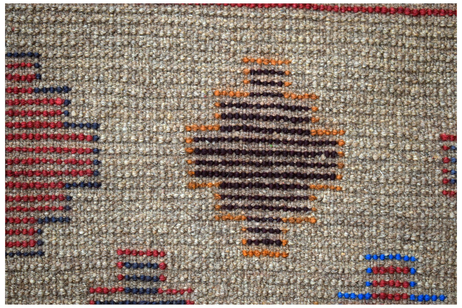 Handmade Afghan Pashm rug featuring geometric diamond patterns in red, blue, and orange on wool.