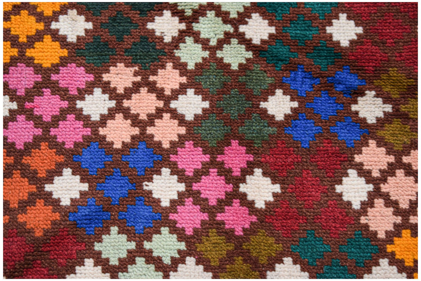 A handmade Afghan Pashm rug featuring a geometric pattern of colorful wool squares on a brown base.