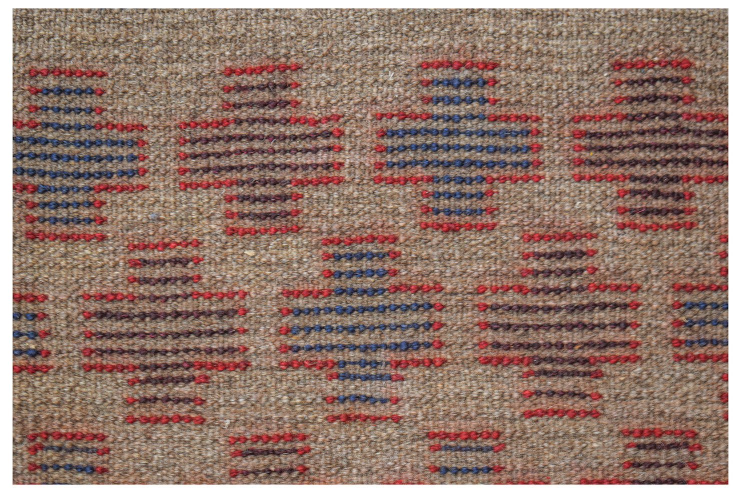 Handmade Afghan Pashm rug featuring a repeating geometric pattern in red, blue, and brown wool.