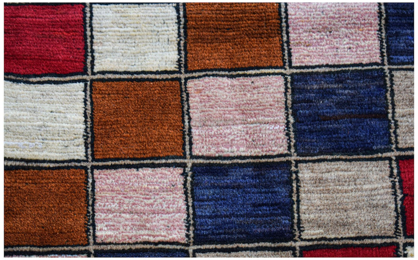 Handmade Afghan Pashm rug featuring a colorful grid pattern of wool squares in various tones.