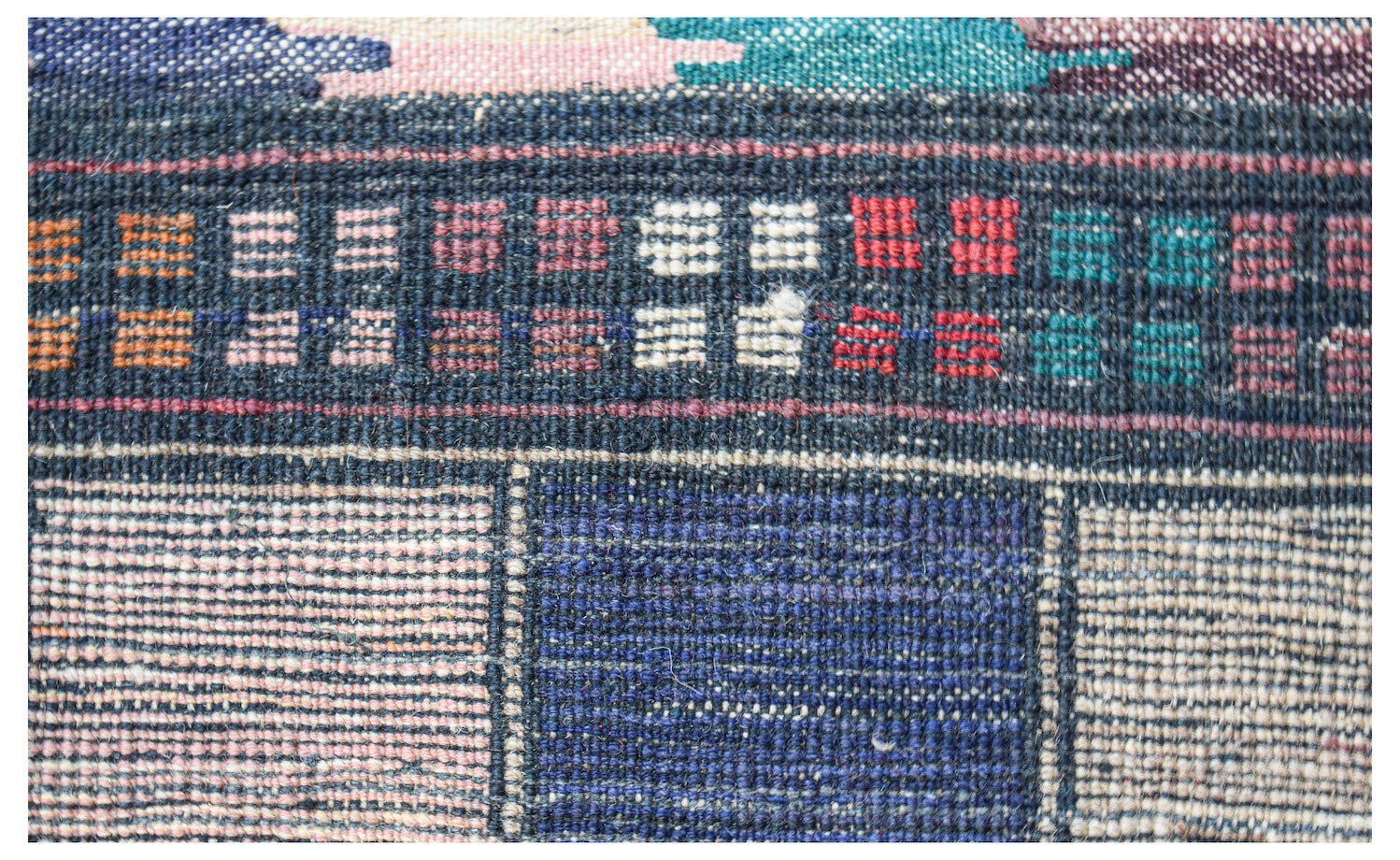 A close-up of a handmade Afghan wool rug featuring a geometric pattern of blue and ivory squares.