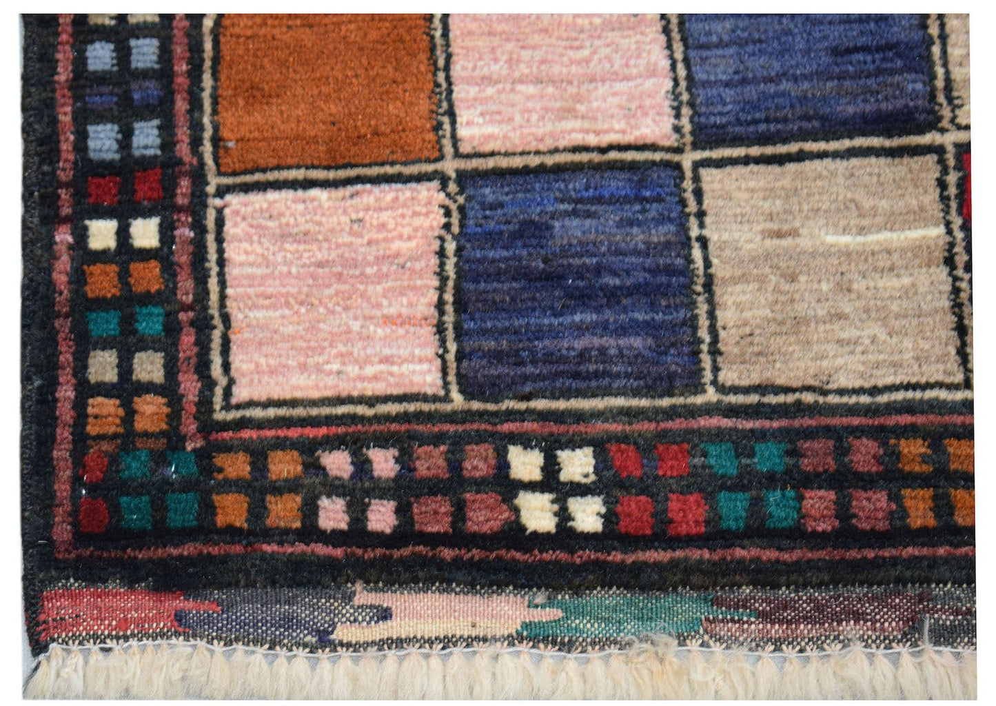 A handmade Afghan Pashm rug featuring a geometric grid of colorful wool squares and a fringed edge.