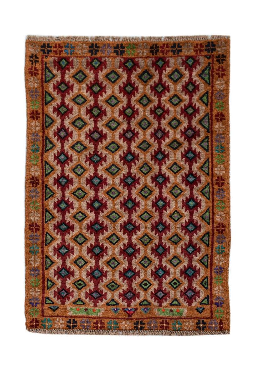 A handmade Afghan Pashm rug featuring a repeating geometric diamond pattern in red, brown, and blue.