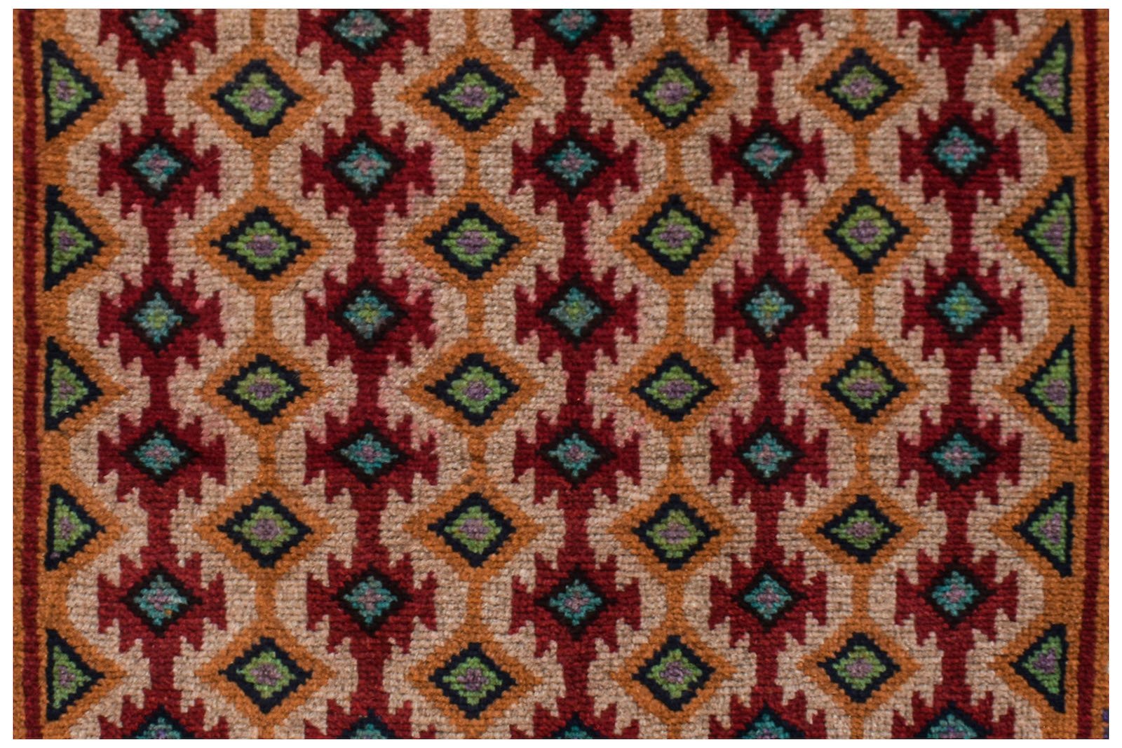 Handmade Afghan Pashm rug featuring a repeating geometric diamond pattern in red, orange, and blue.
