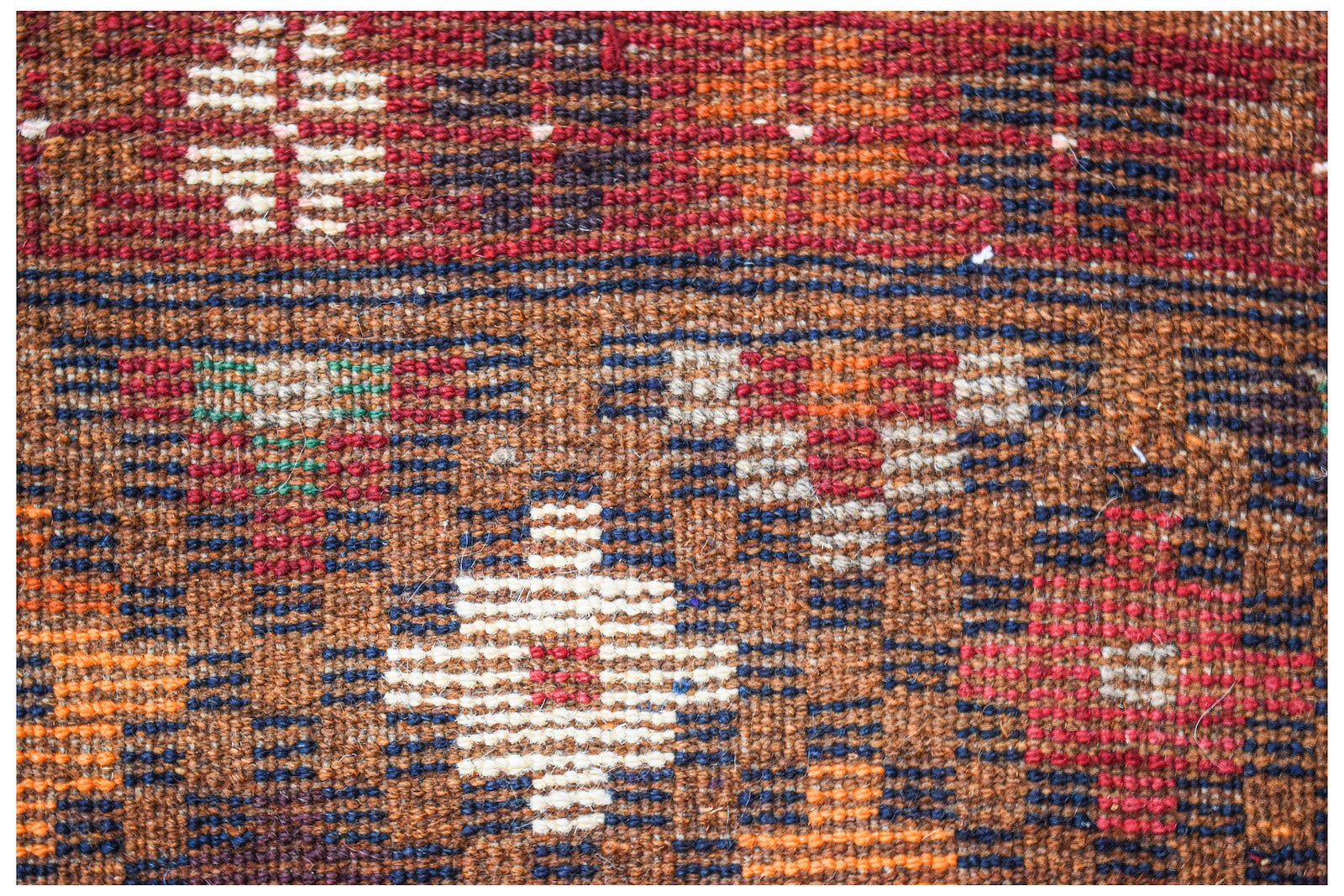 A handmade Afghan Pashm rug featuring a geometric tribal pattern in shades of red, brown, and ivory.