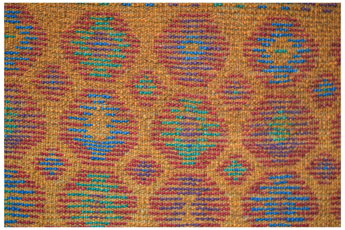 Handmade Afghan Pashm rug featuring a repeating pattern of colorful geometric circles on orange.