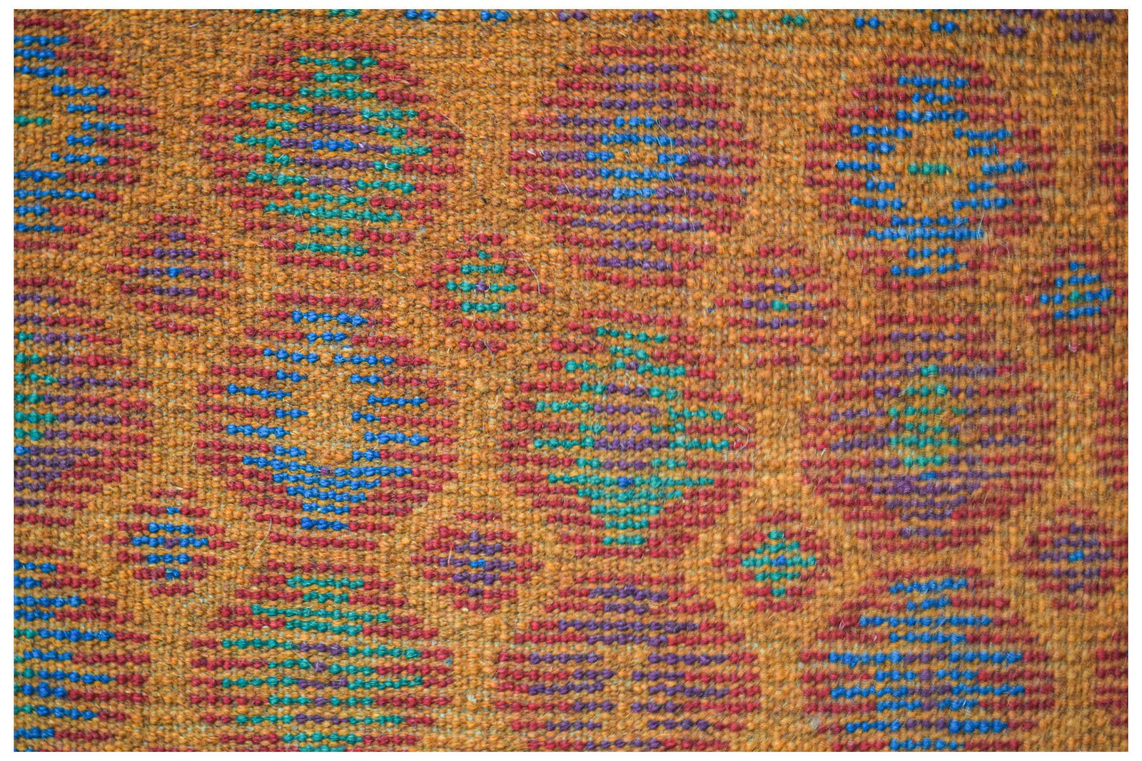 Handmade Afghan Pashm rug featuring a repeating pattern of colorful geometric circles on orange.