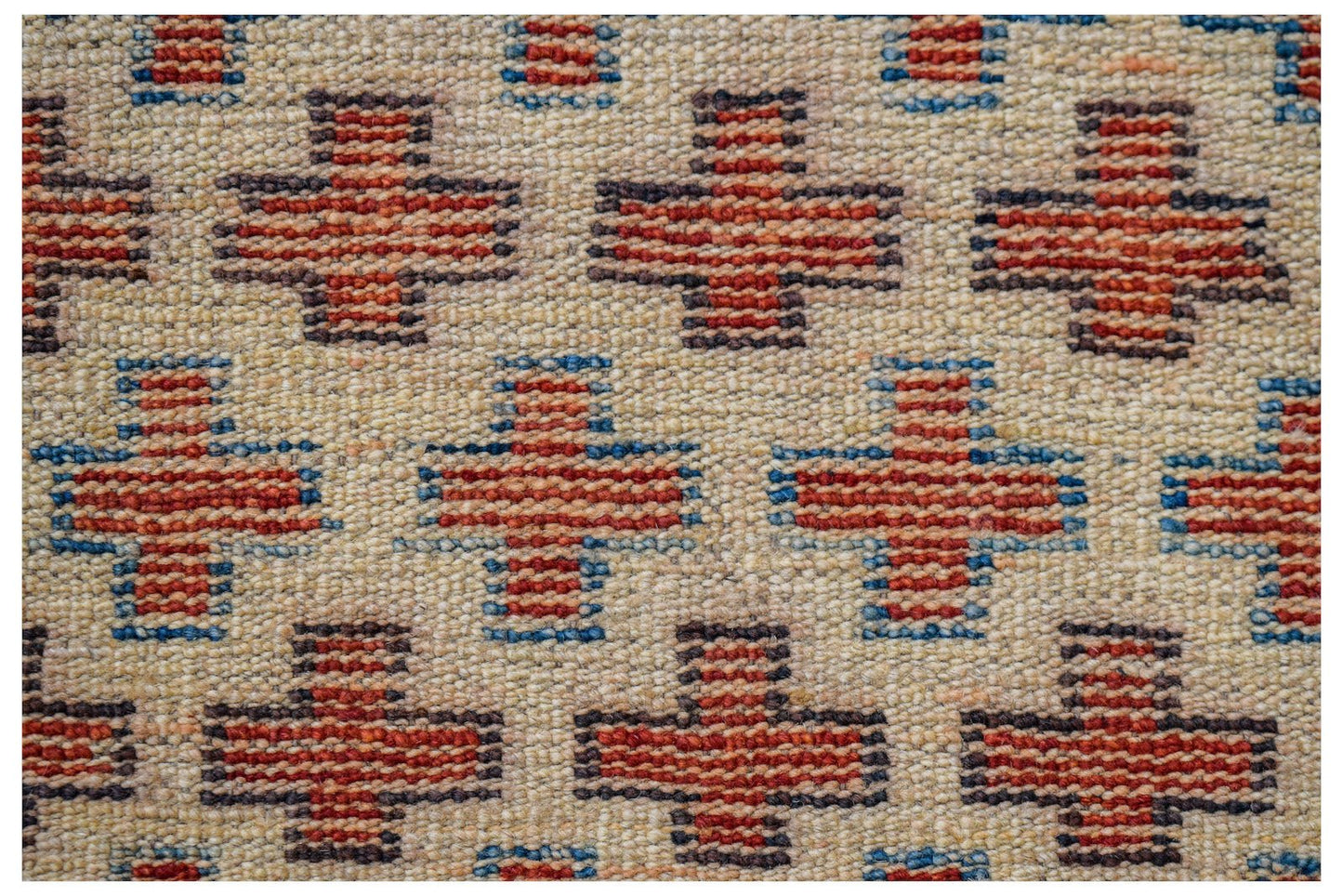 Handmade Afghan Pashm rug featuring a repeating pattern of red and blue crosses on an ivory field.