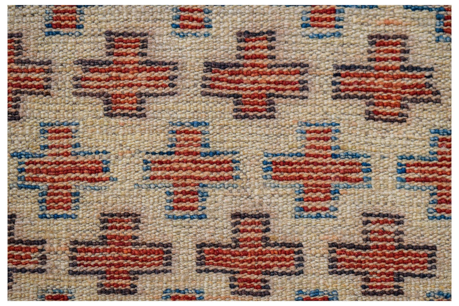 Handmade Afghan Pashm rug featuring a repeating pattern of red and blue crosses on an ivory field.