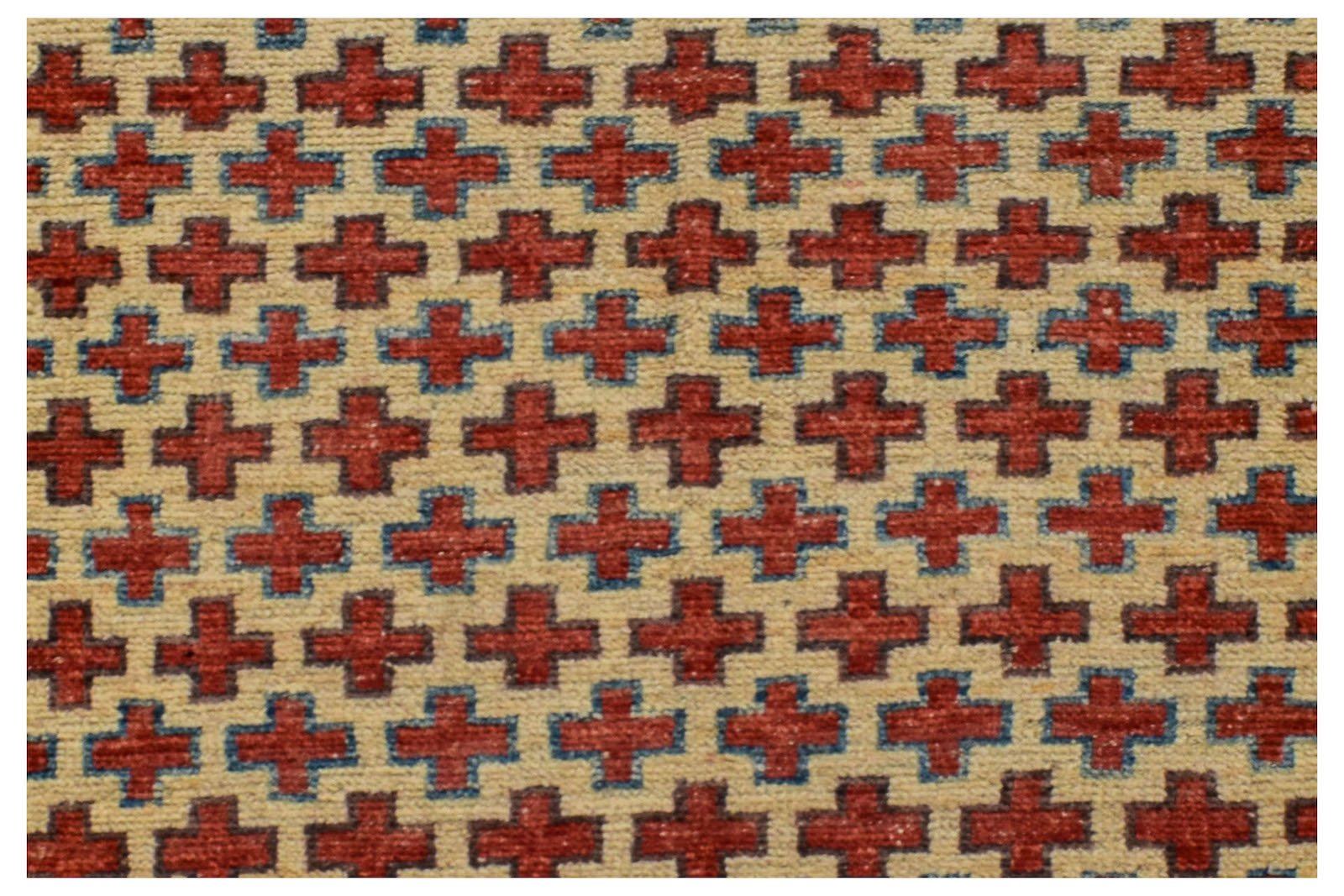 A handmade Afghan Pashm rug featuring a repeating pattern of red crosses on an ivory background.