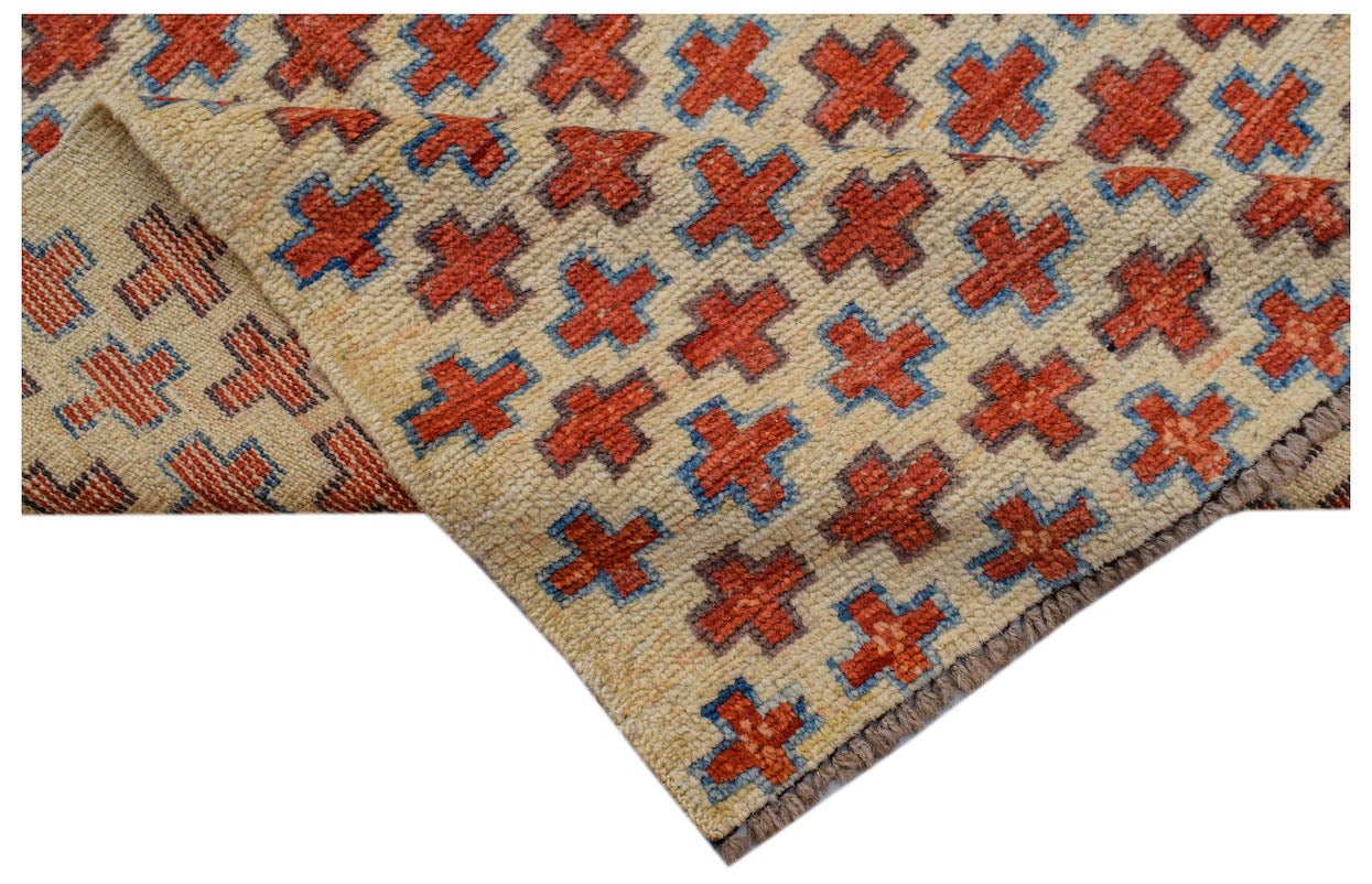Handmade Afghan Pashm rug featuring a repeating red cross pattern on a cream wool background.