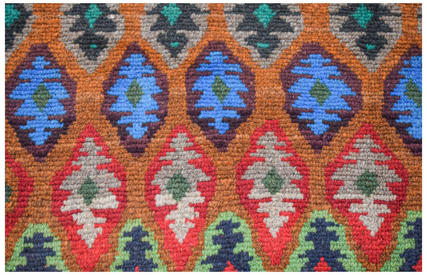 Handmade Afghan wool rug featuring a repeating diamond pattern in blue, red, and green tones.