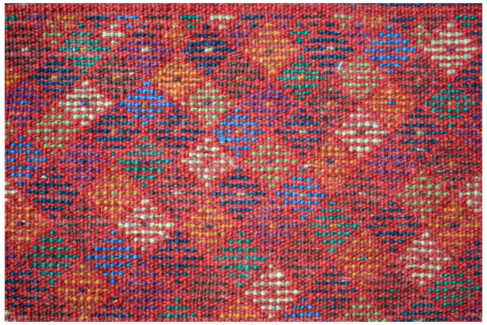 Handmade Afghan Pashm rug featuring a geometric diamond pattern in red, blue, and ivory wool.