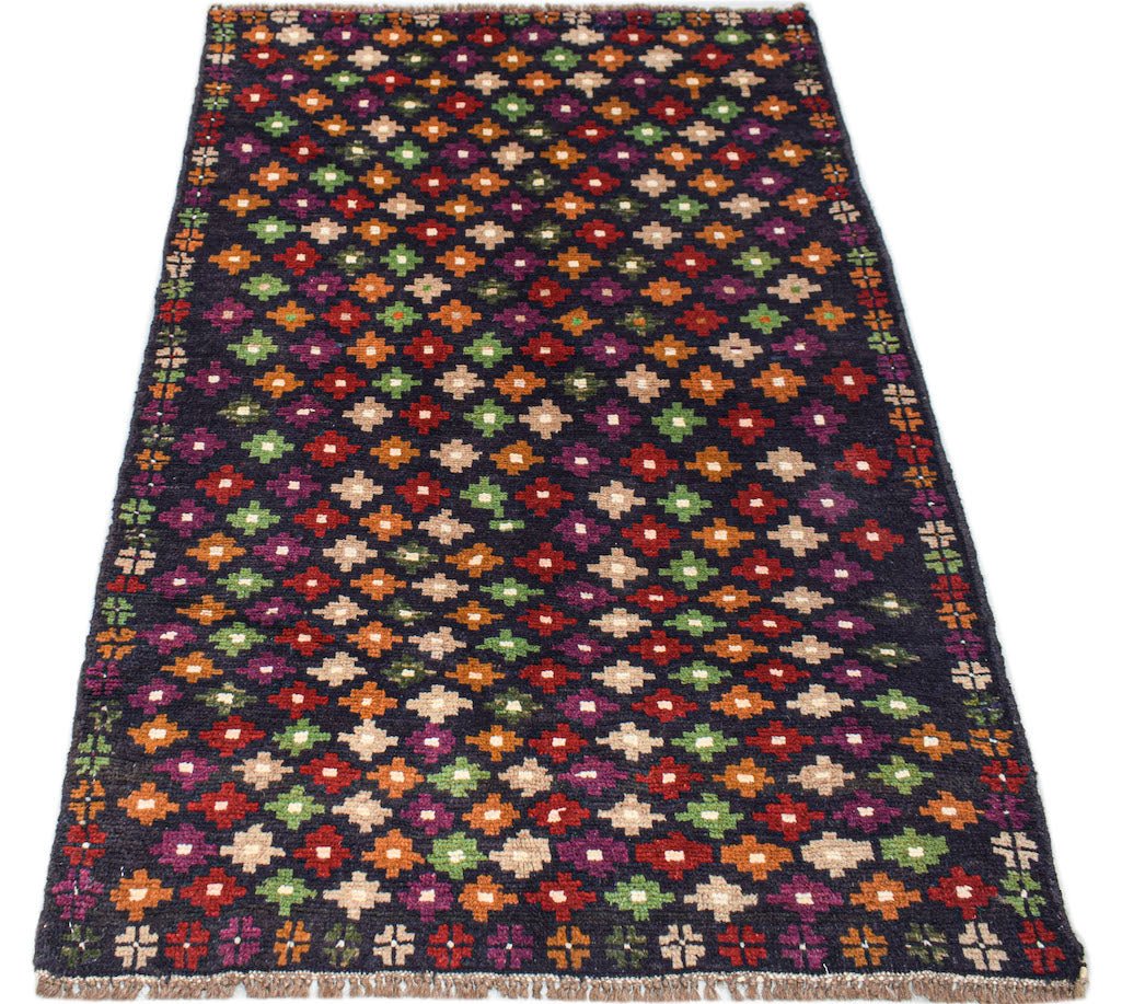 Afghan Pashm rug with a dark background and a colorful geometric pattern.