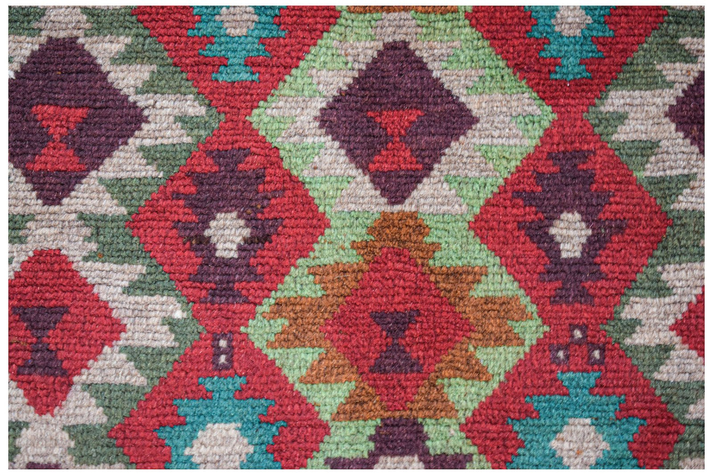 Handmade Afghan wool rug featuring a geometric diamond pattern in red, brown, green, and ivory.