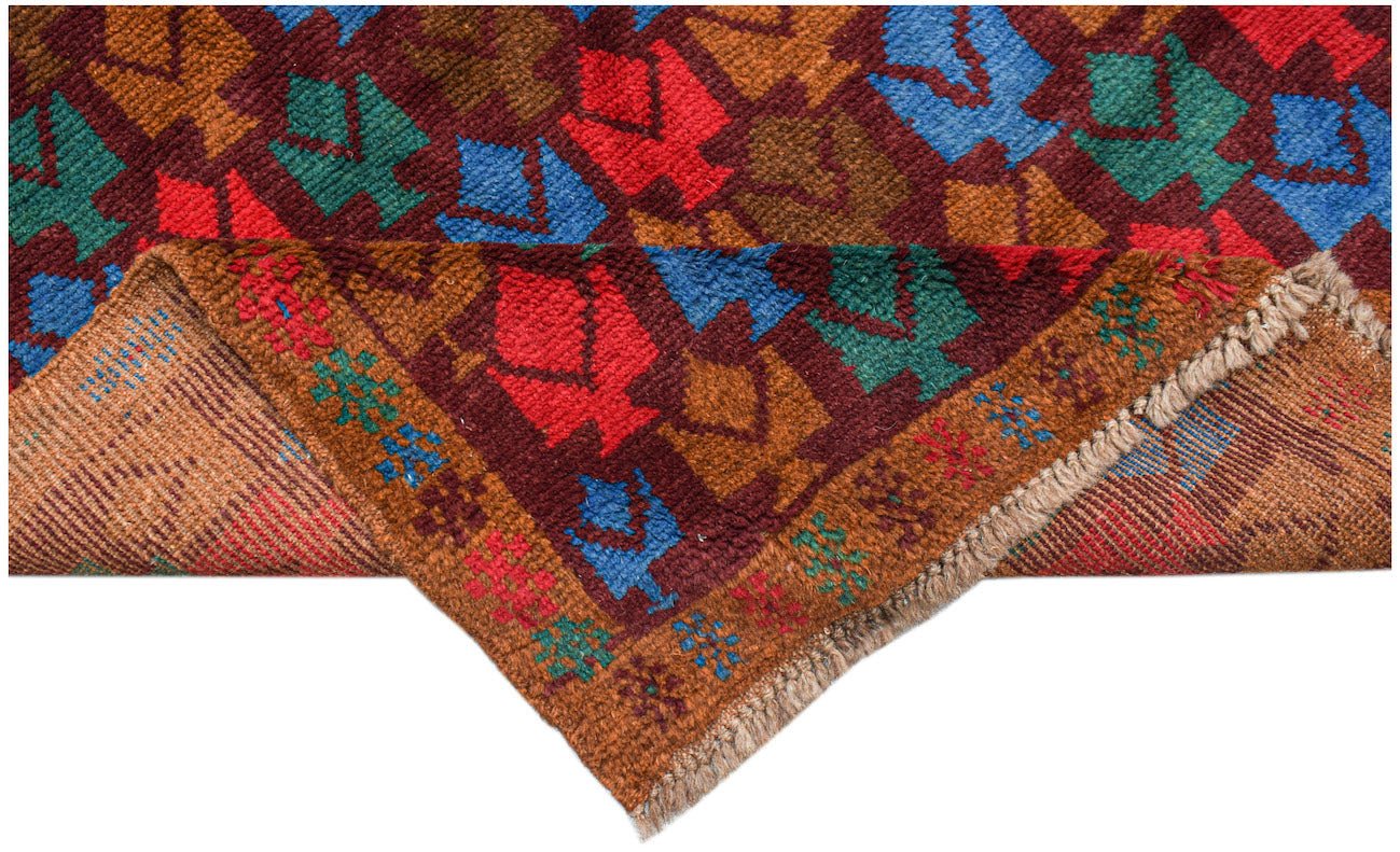Handmade Afghan Pashm rug featuring a geometric tribal pattern in red, blue, and brown wool.