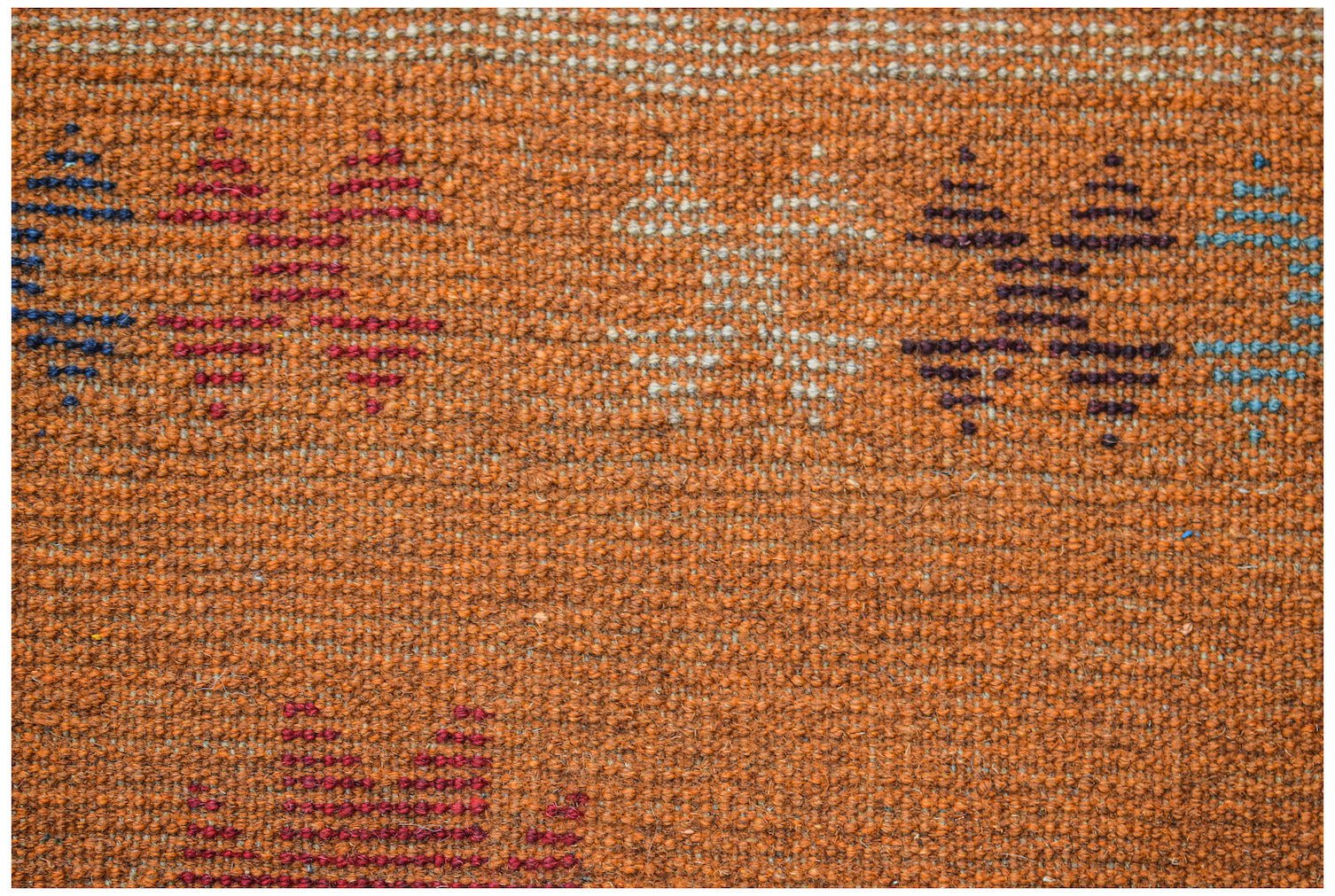 Handmade Afghan Pashm rug featuring a textured orange wool base with geometric tribal patterns.