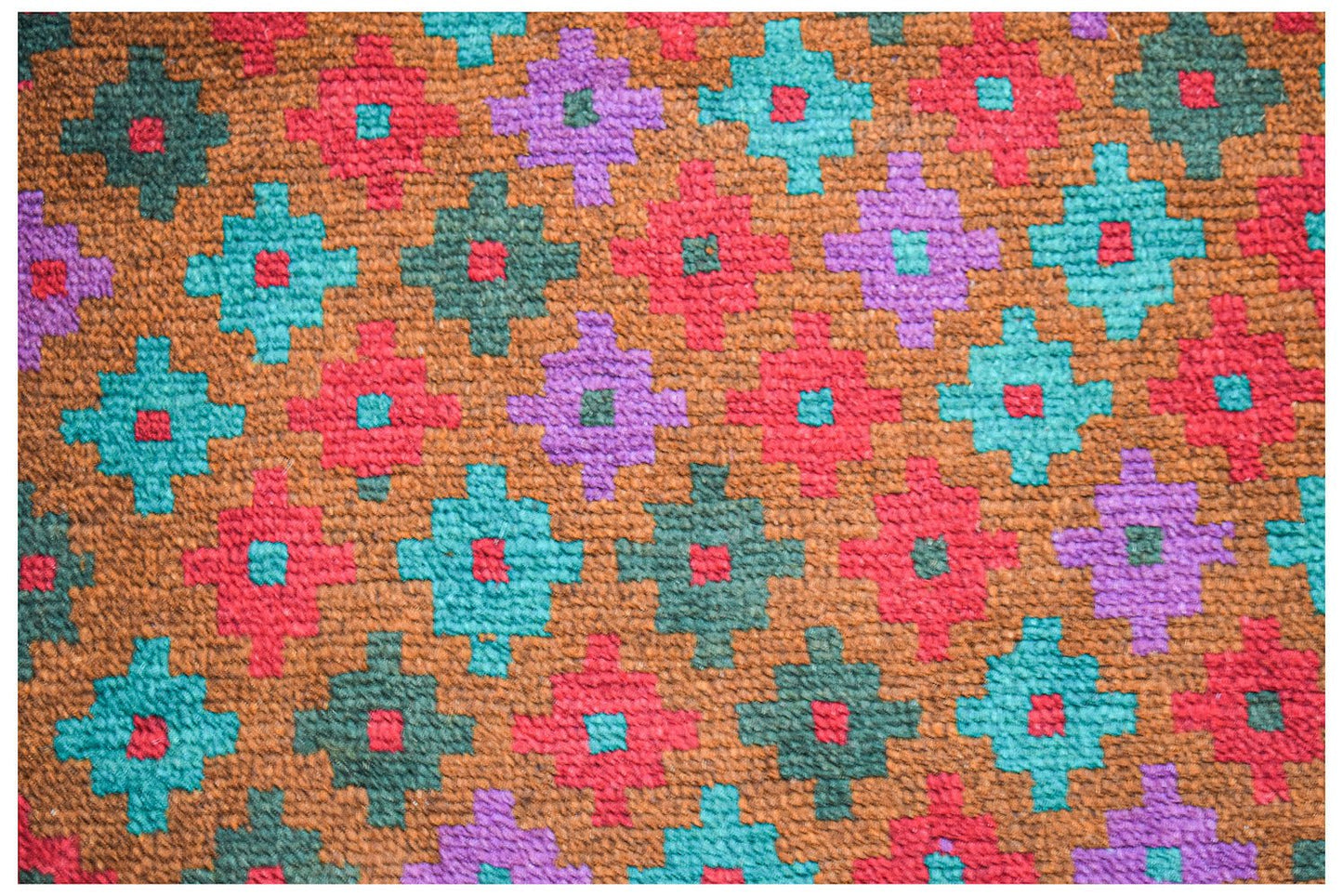 Handmade Afghan wool rug featuring a repeating geometric pattern in red, teal, purple, and brown.