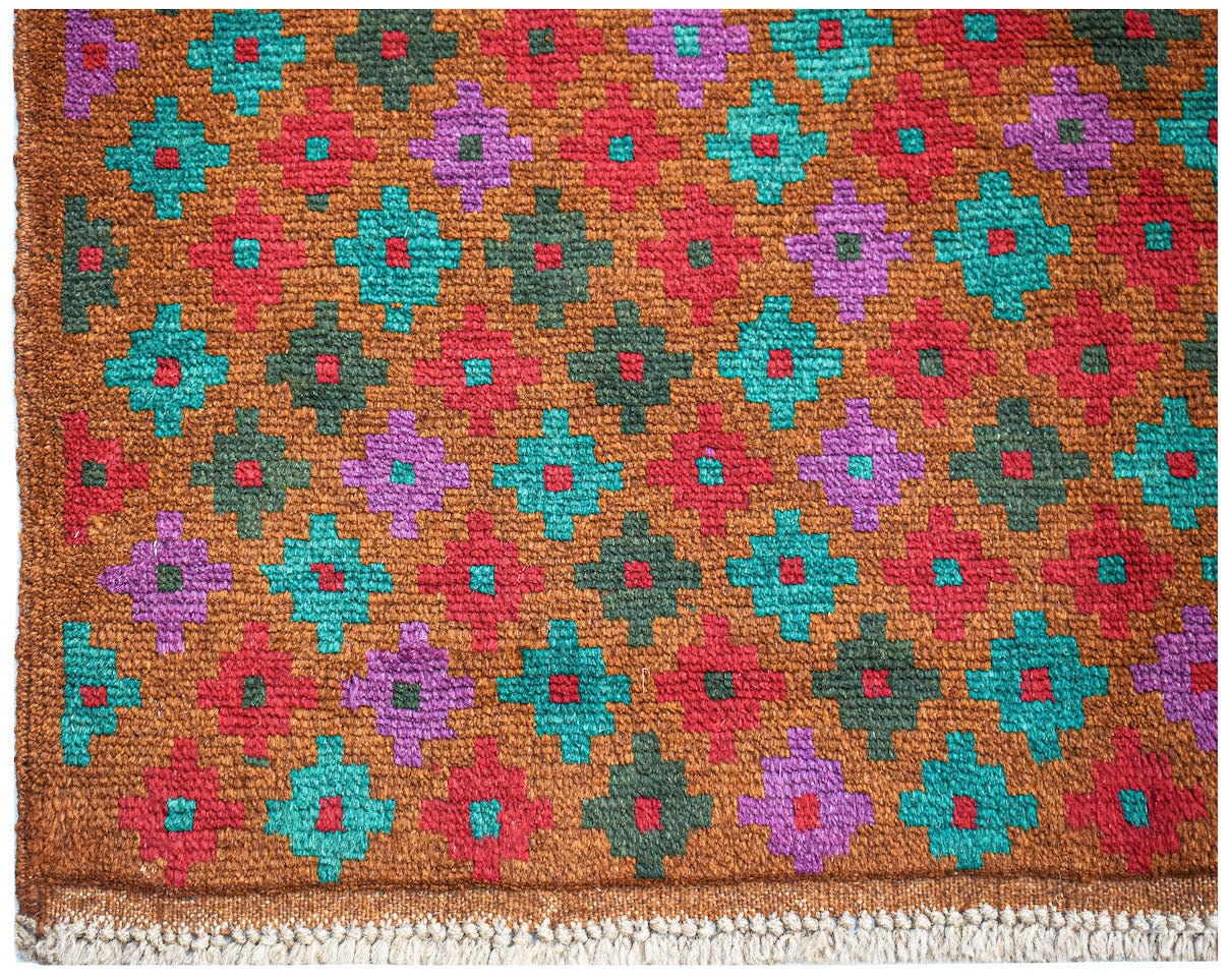 Handmade Afghan Pashm rug featuring a repeating geometric pattern in red, teal, and purple.
