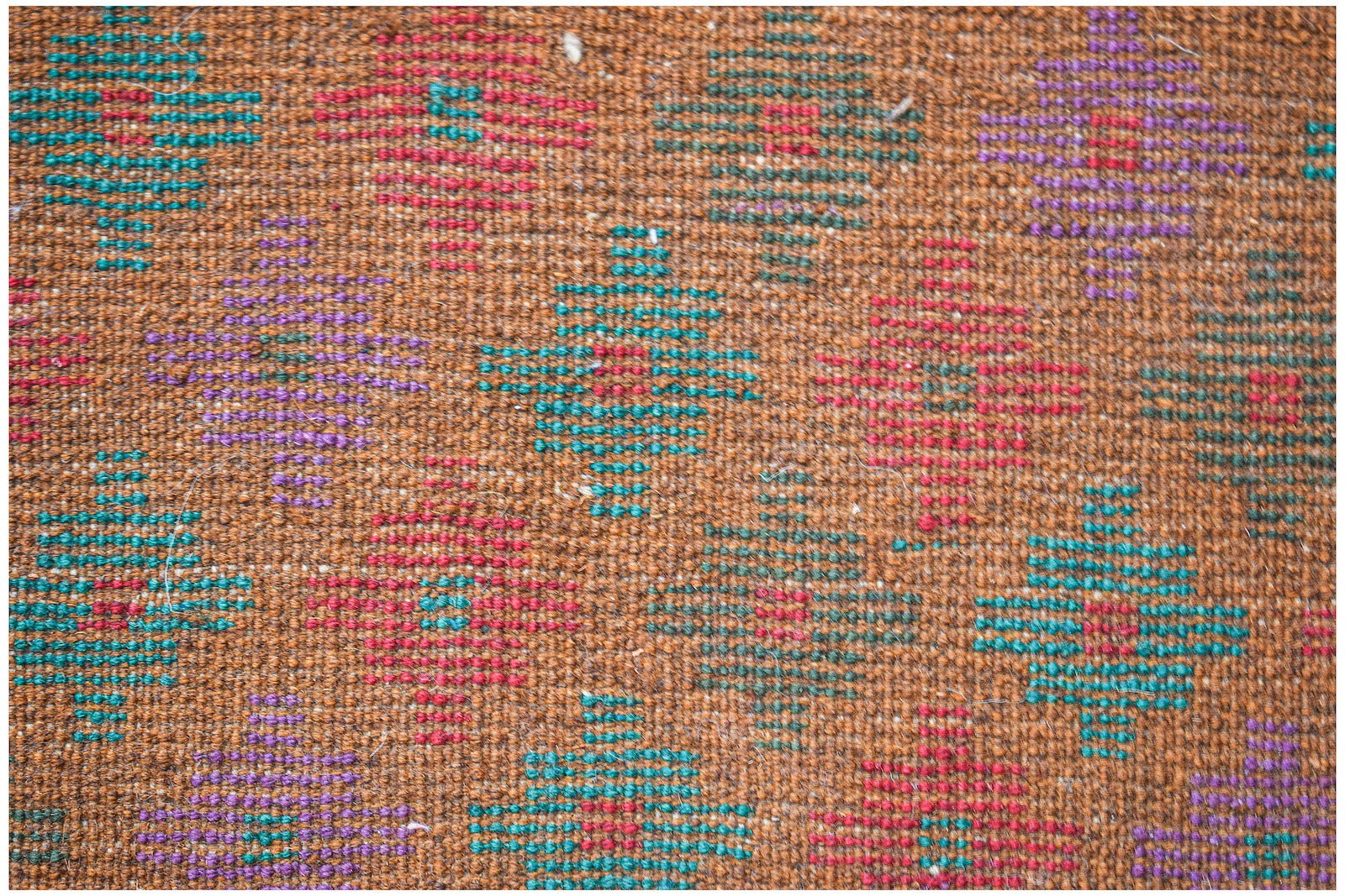 Handmade Afghan Pashm rug featuring a geometric diamond pattern in red, blue, and purple on brown.