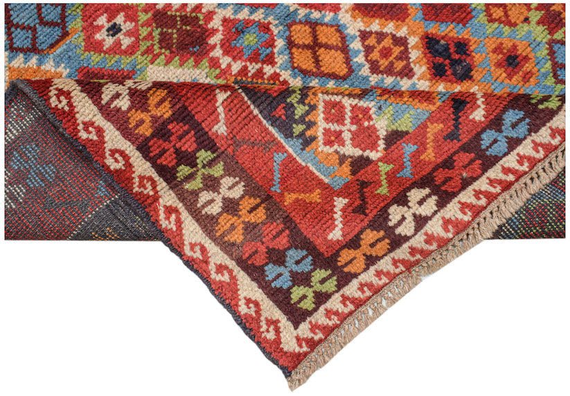 Handmade Afghan Pashm rug featuring a geometric tribal pattern in deep red, blue, and brown tones.