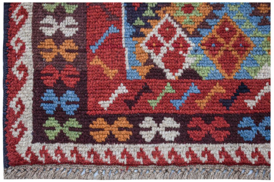 Handmade Afghan Pashm rug featuring a geometric tribal pattern in red, blue, and ivory wool.