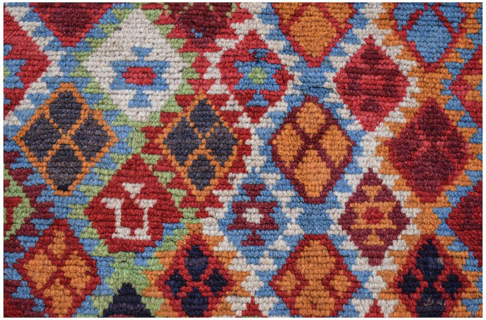 A handmade Afghan Pashm rug featuring a vibrant geometric diamond pattern in red, blue, and orange.