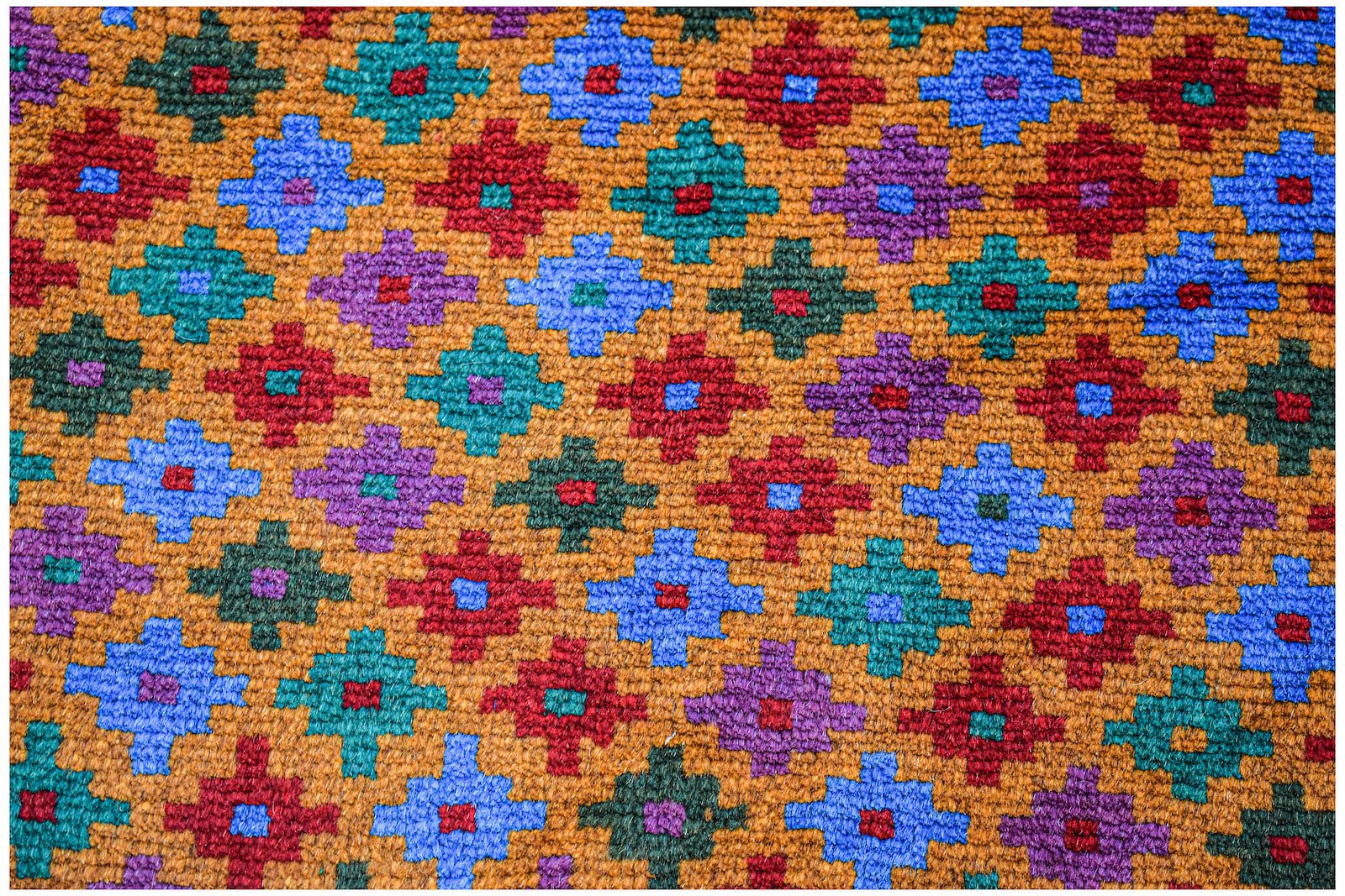 Handmade Afghan wool rug featuring a repeating geometric pattern in red, blue, green, and purple.