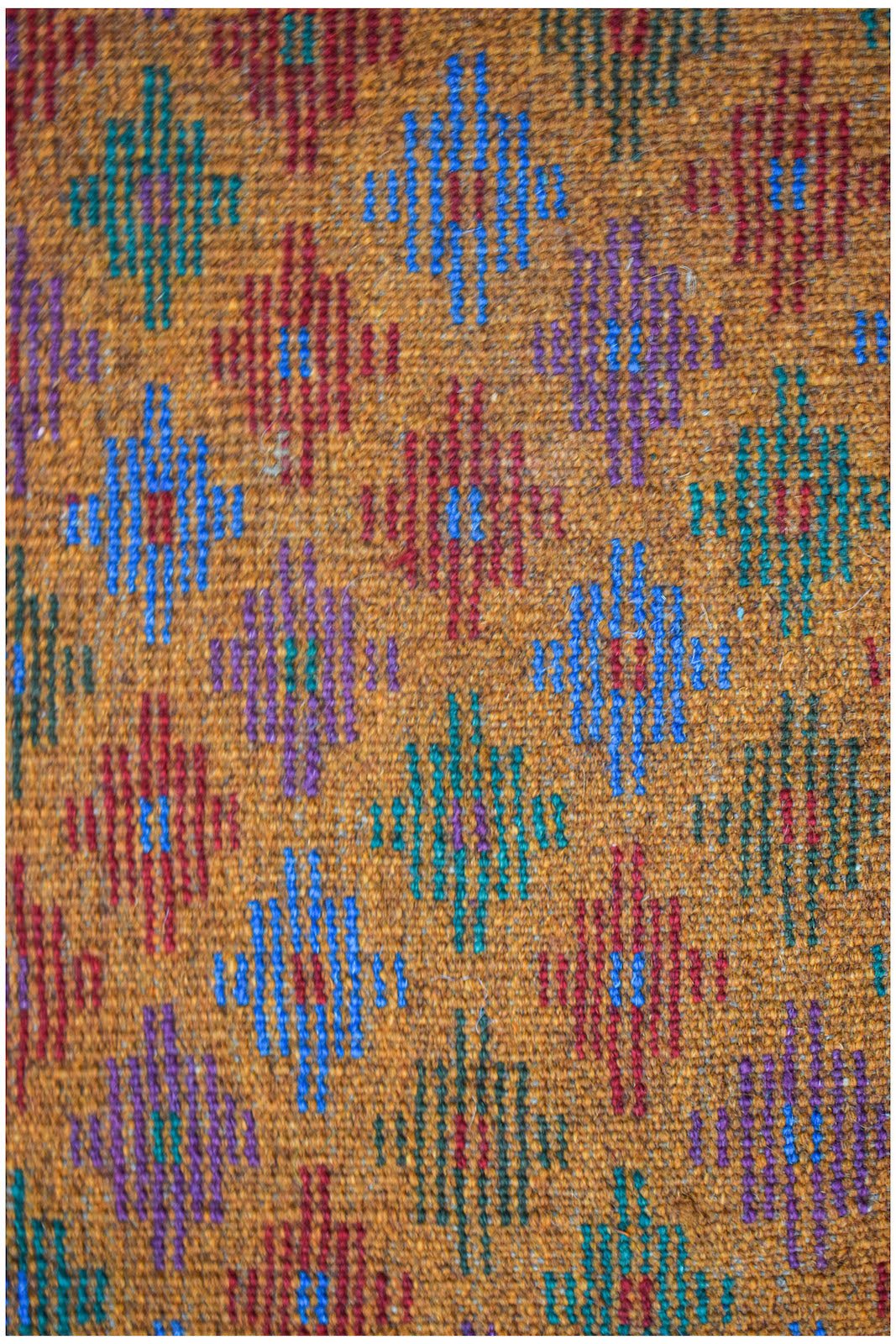 Handmade Afghan Pashm rug featuring a repeating diamond pattern in vibrant colors on a brown base.
